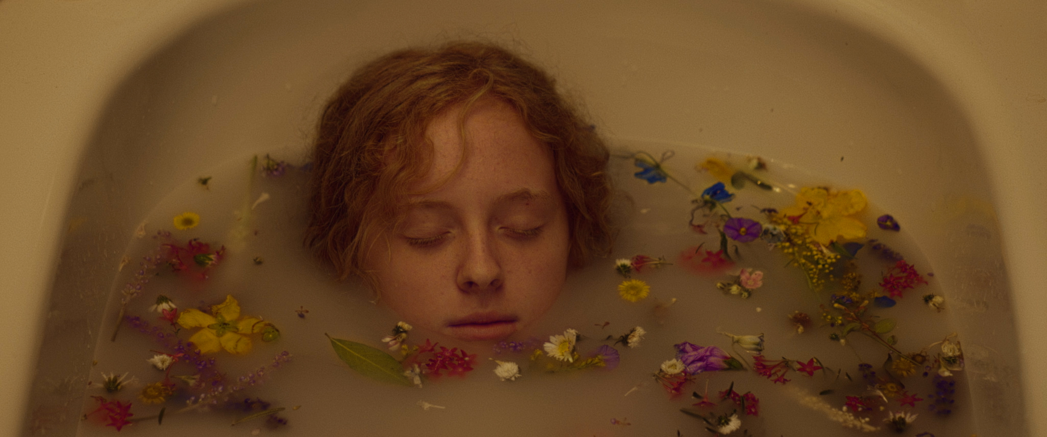 A girl in a flower-filled bath in warm light