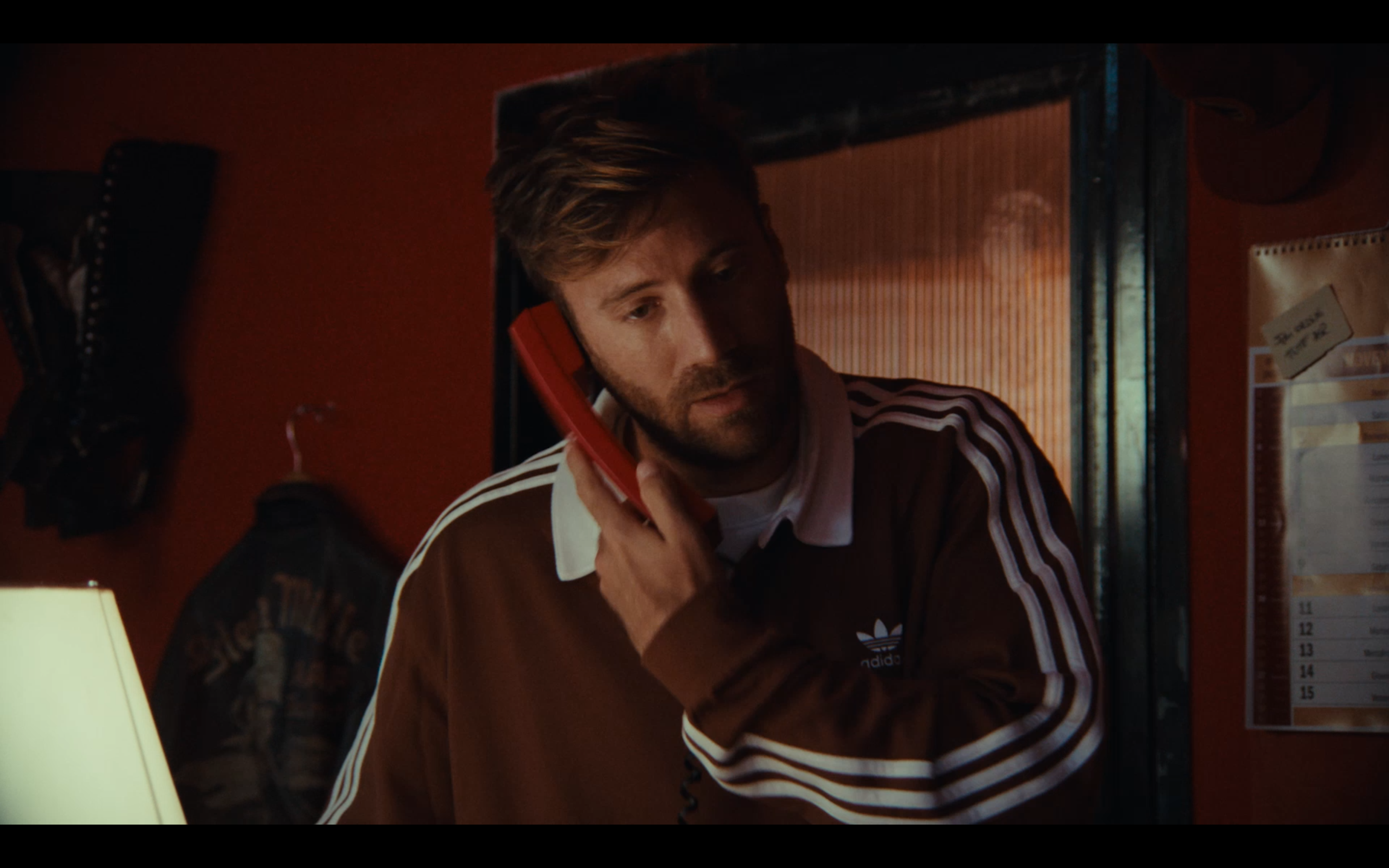 A portrait with a red telephone and an Adidas tracksuit
