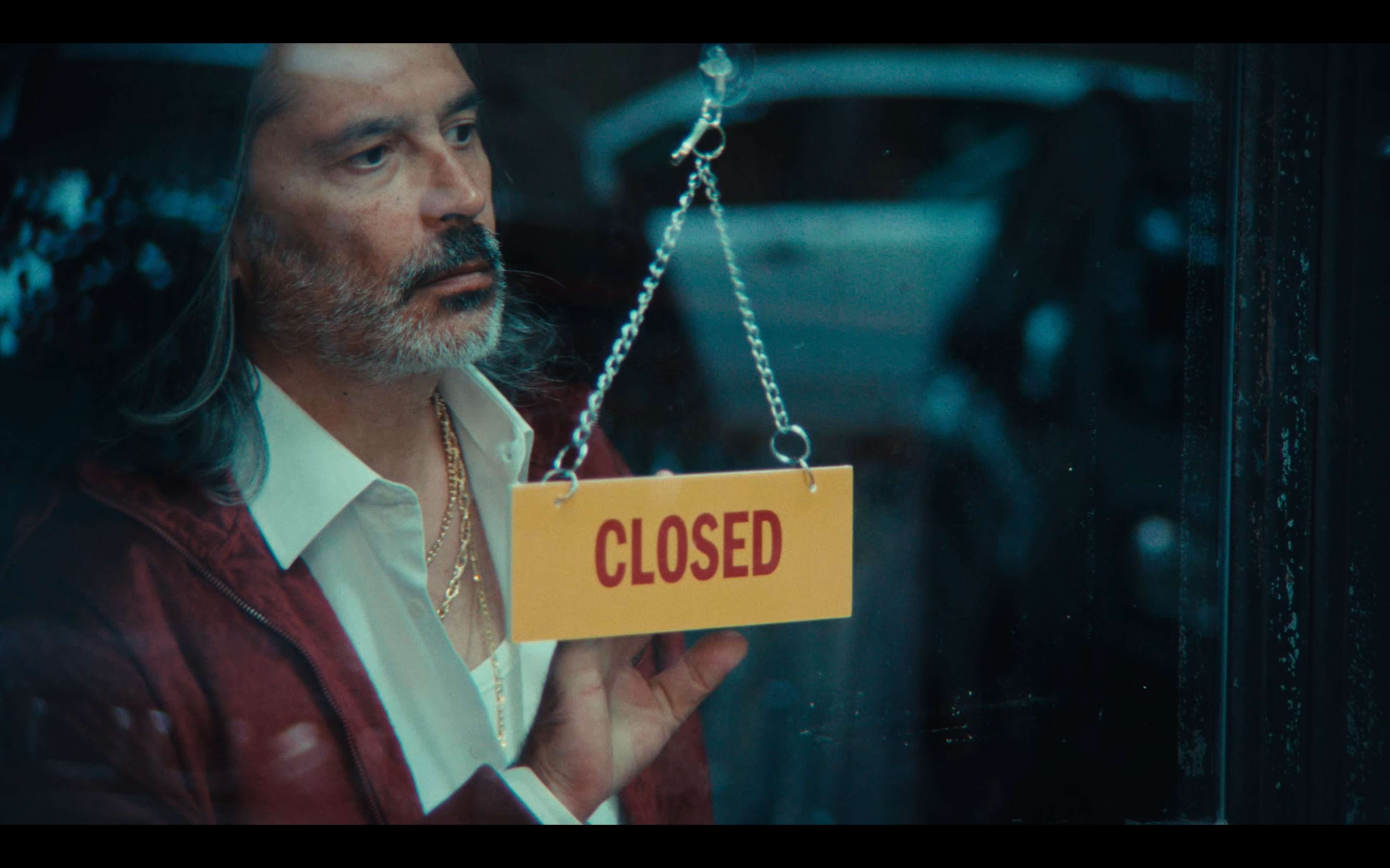 A portrait through the window with a Closed sign and cyan reflections