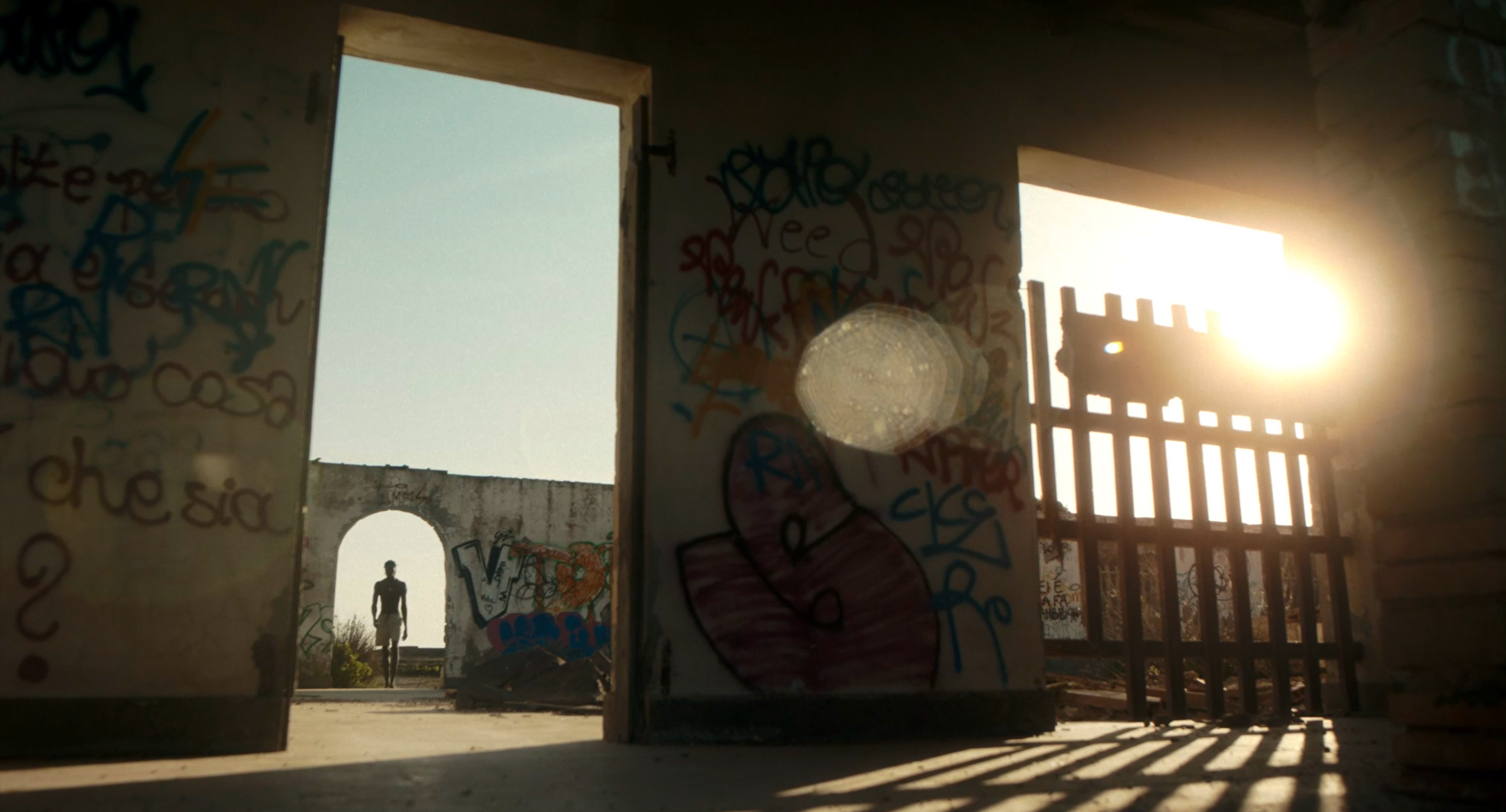 A man seen through a doorway in a sunlit abandoned building