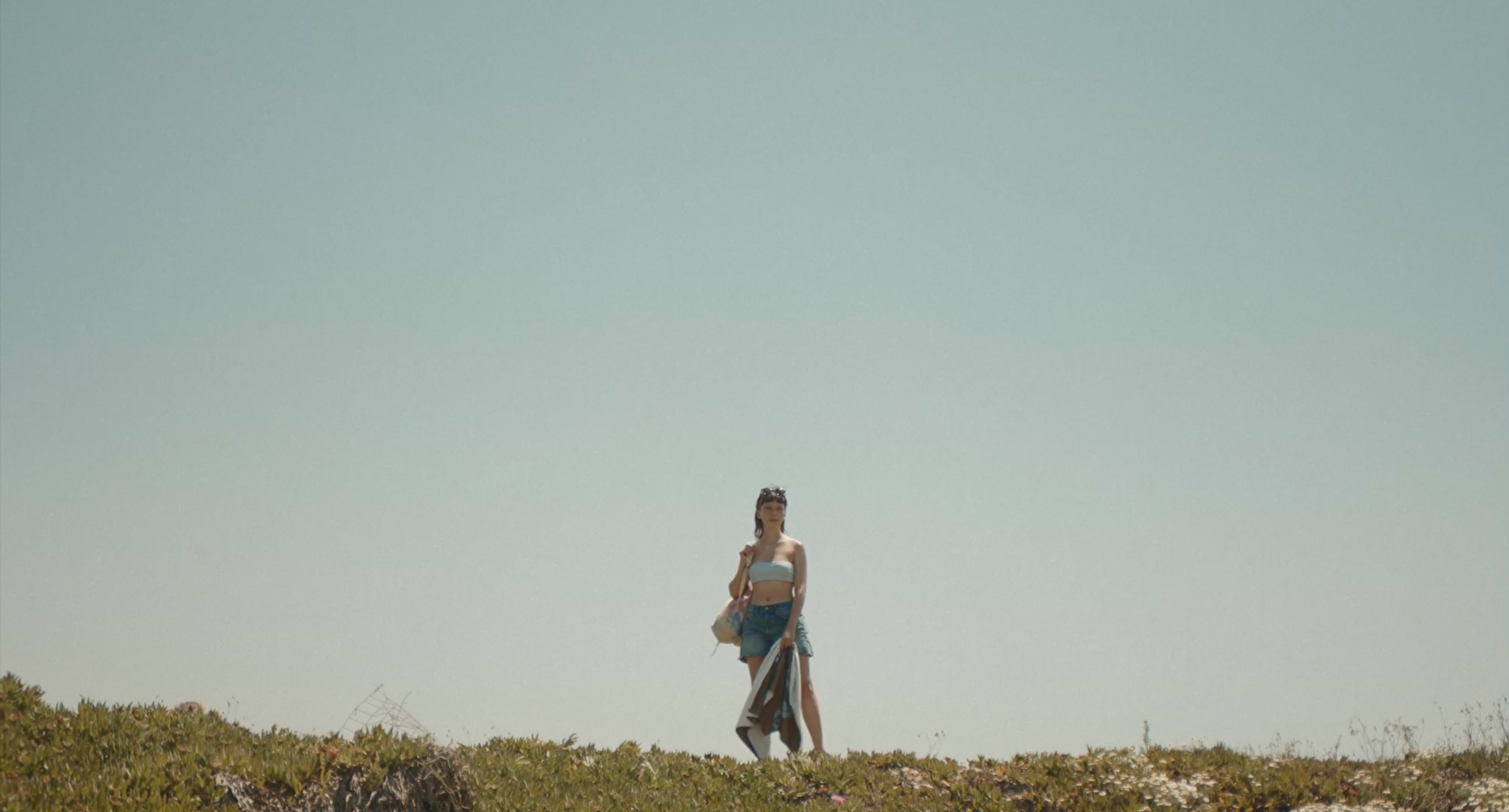 A woman standing on a rise against a pale sky