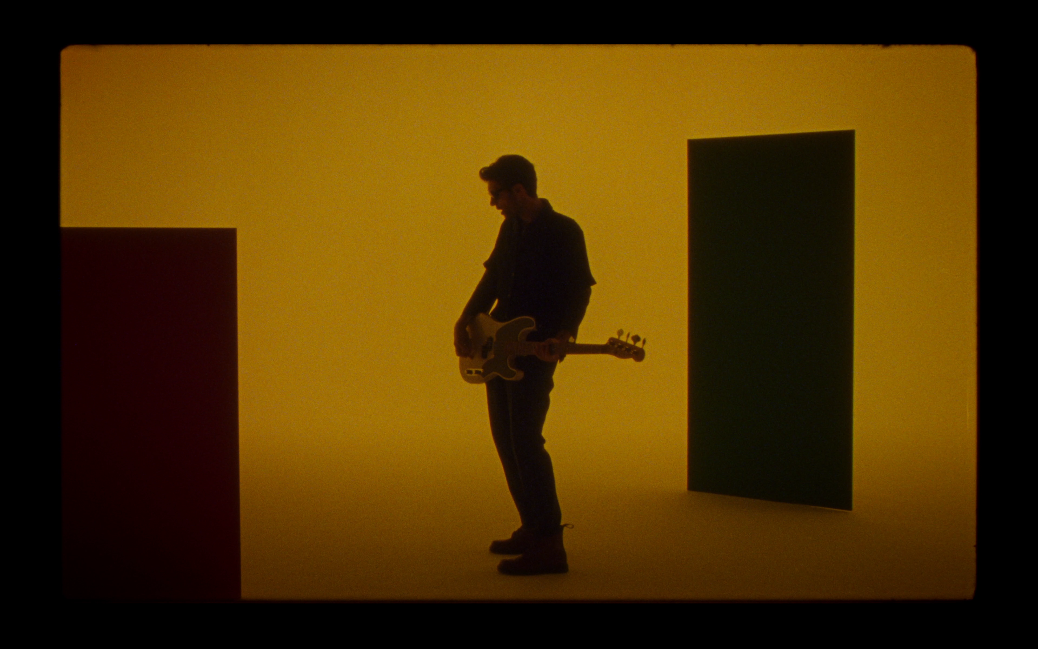 Dodicianni playing bass against a yellow wall
