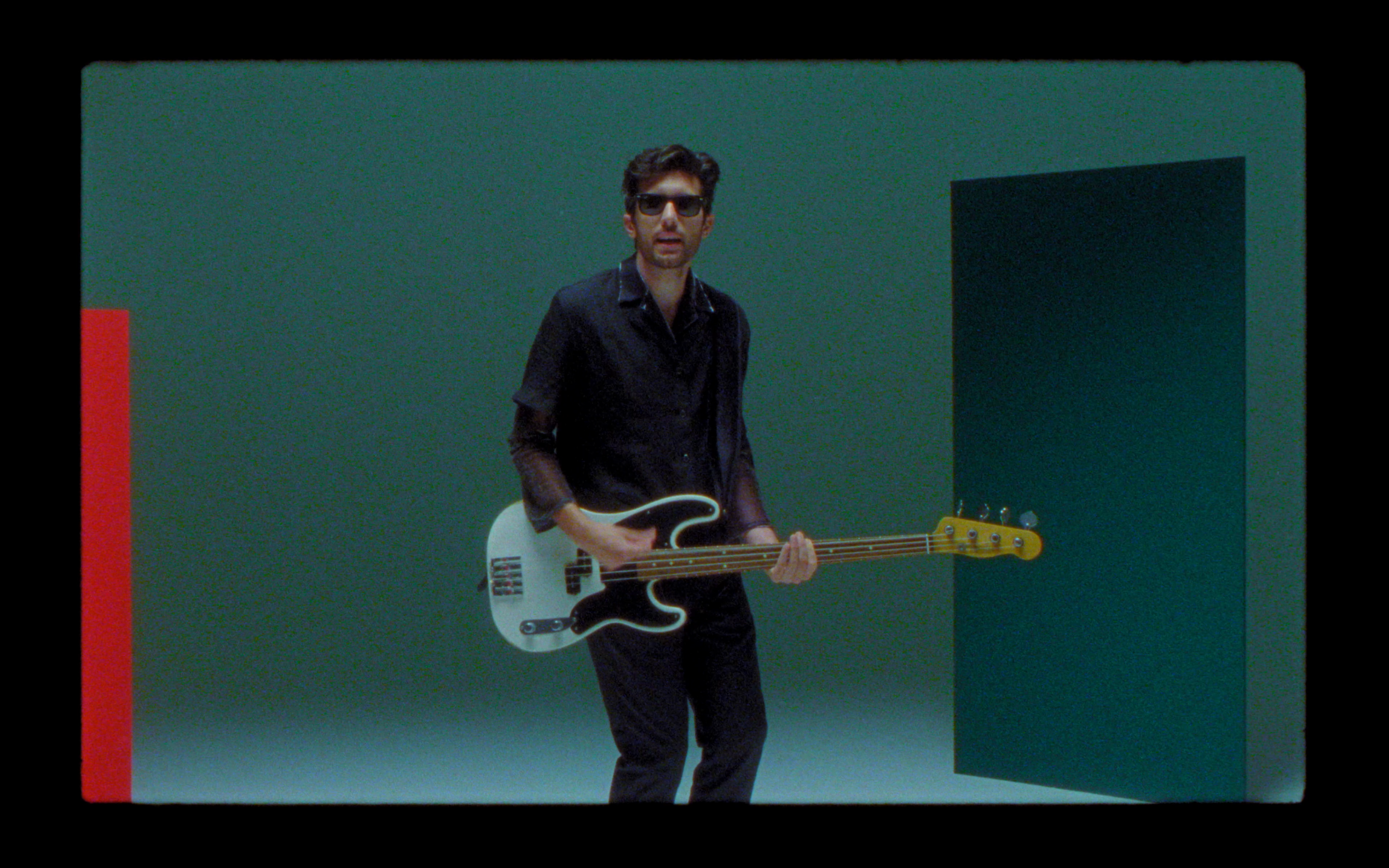 Dodicianni playing bass against a green wall