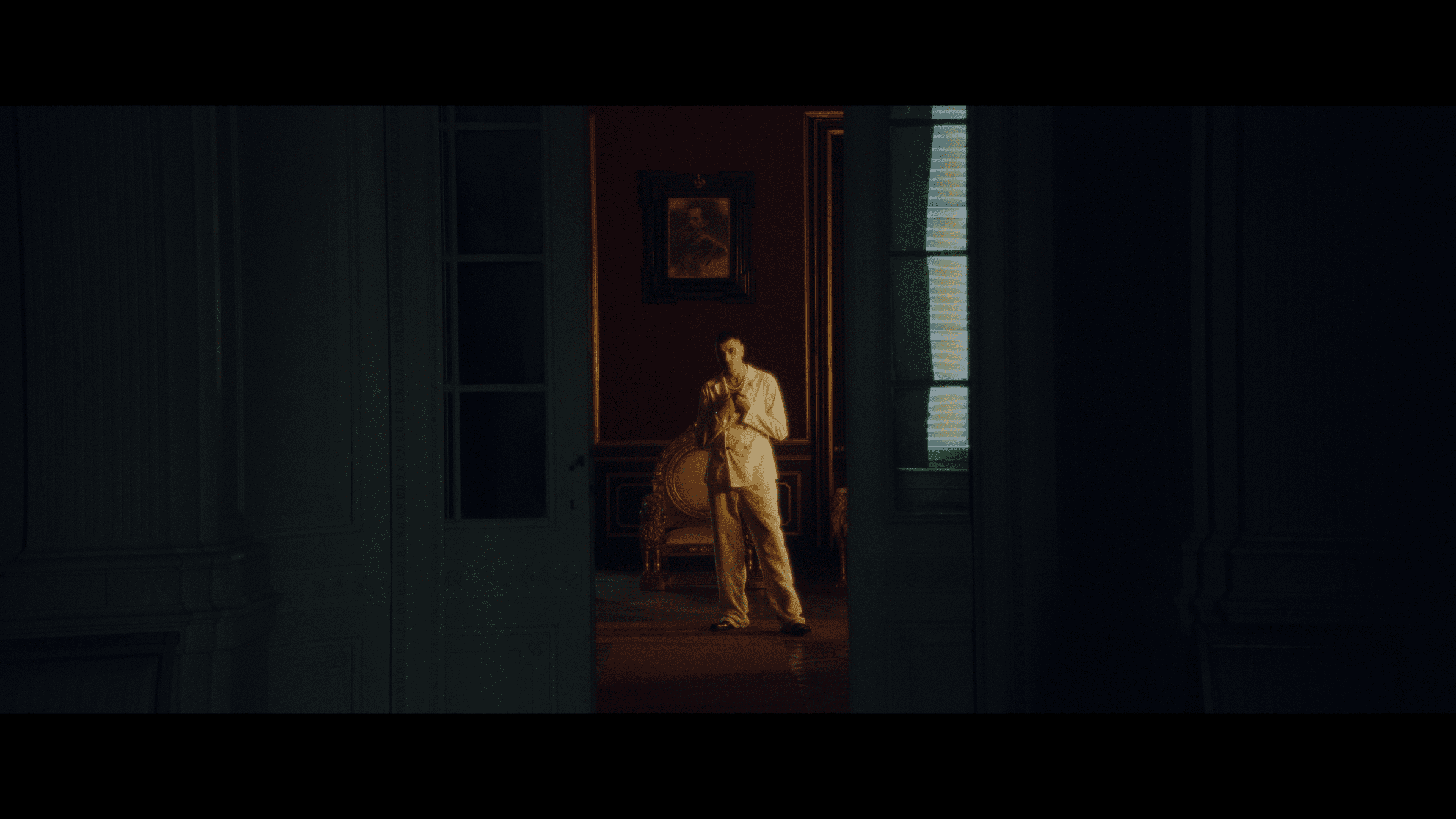 An artist in a pale suit framed by dark doorways