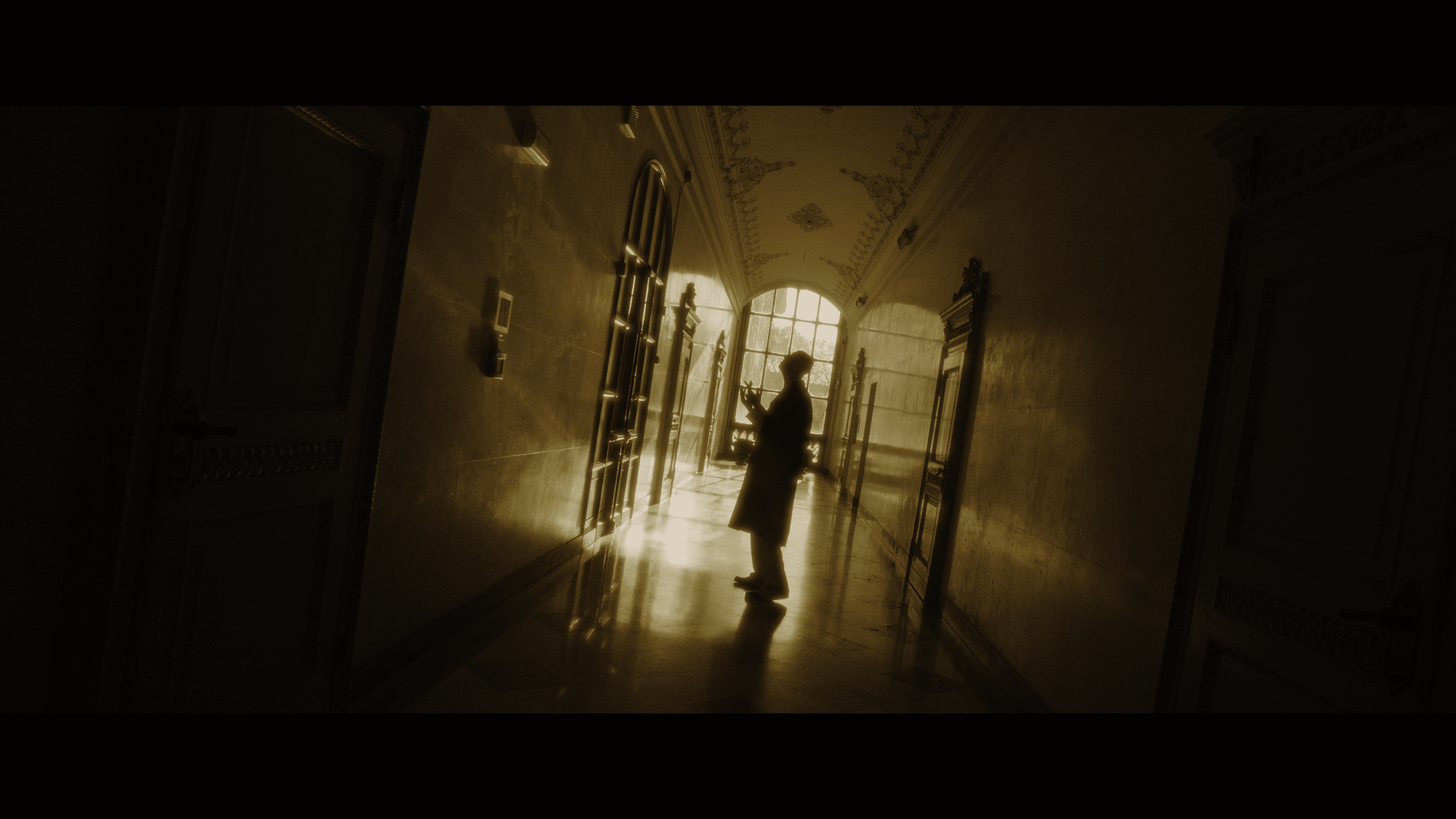 A silhouetted artist in a sloping golden-lit corridor