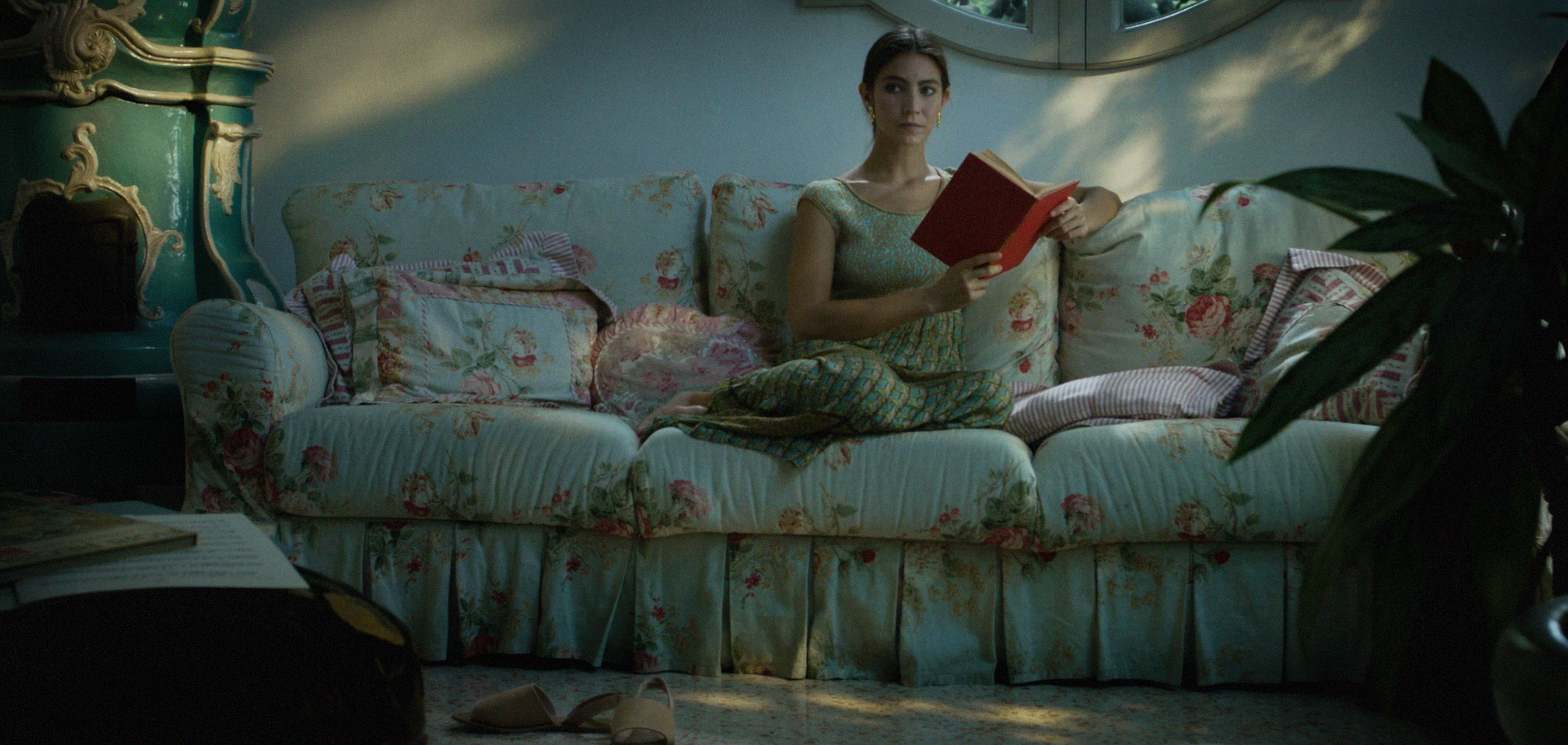 A woman reading on a floral sofa in daylight