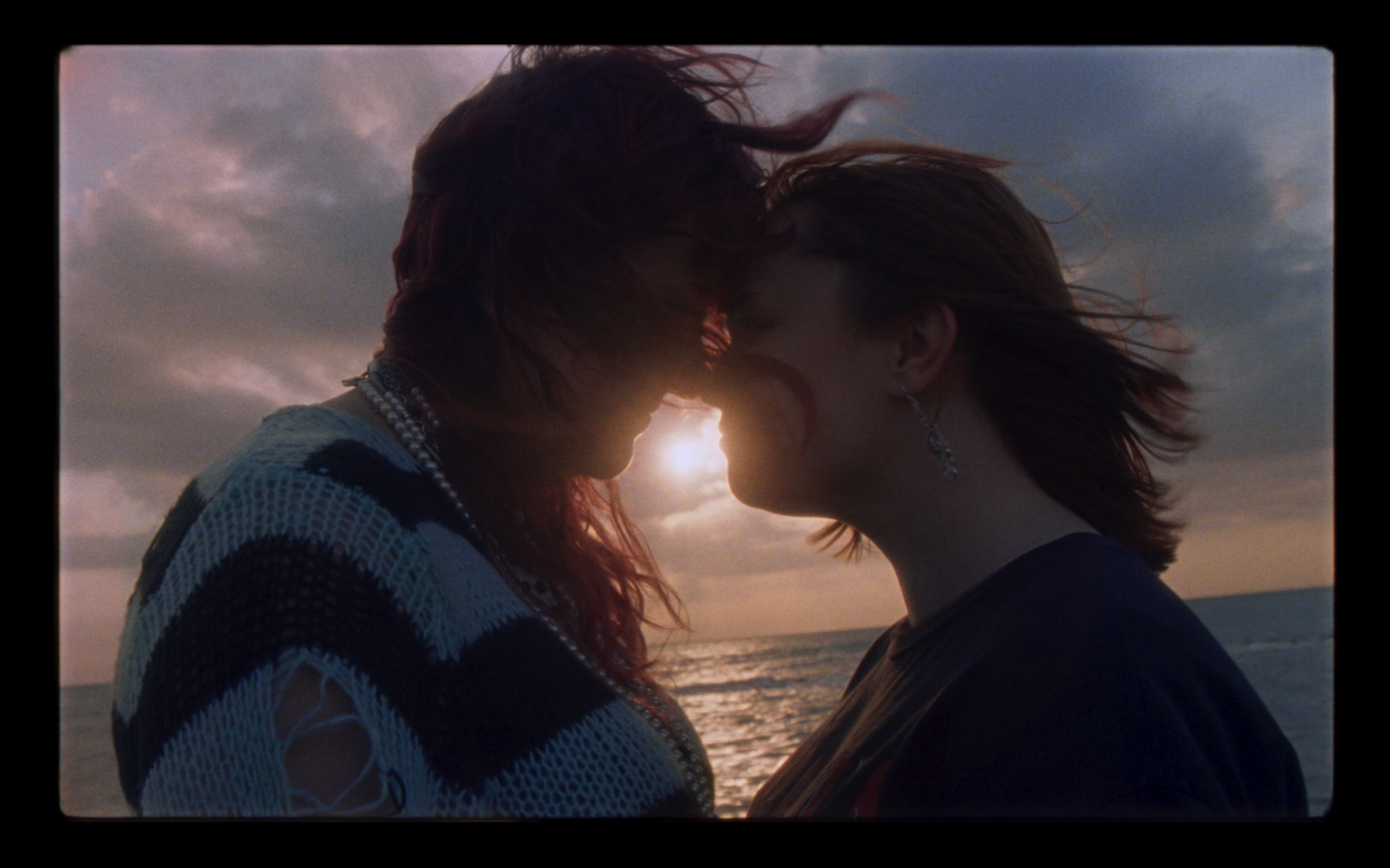 Two people together beside the sea at sunset