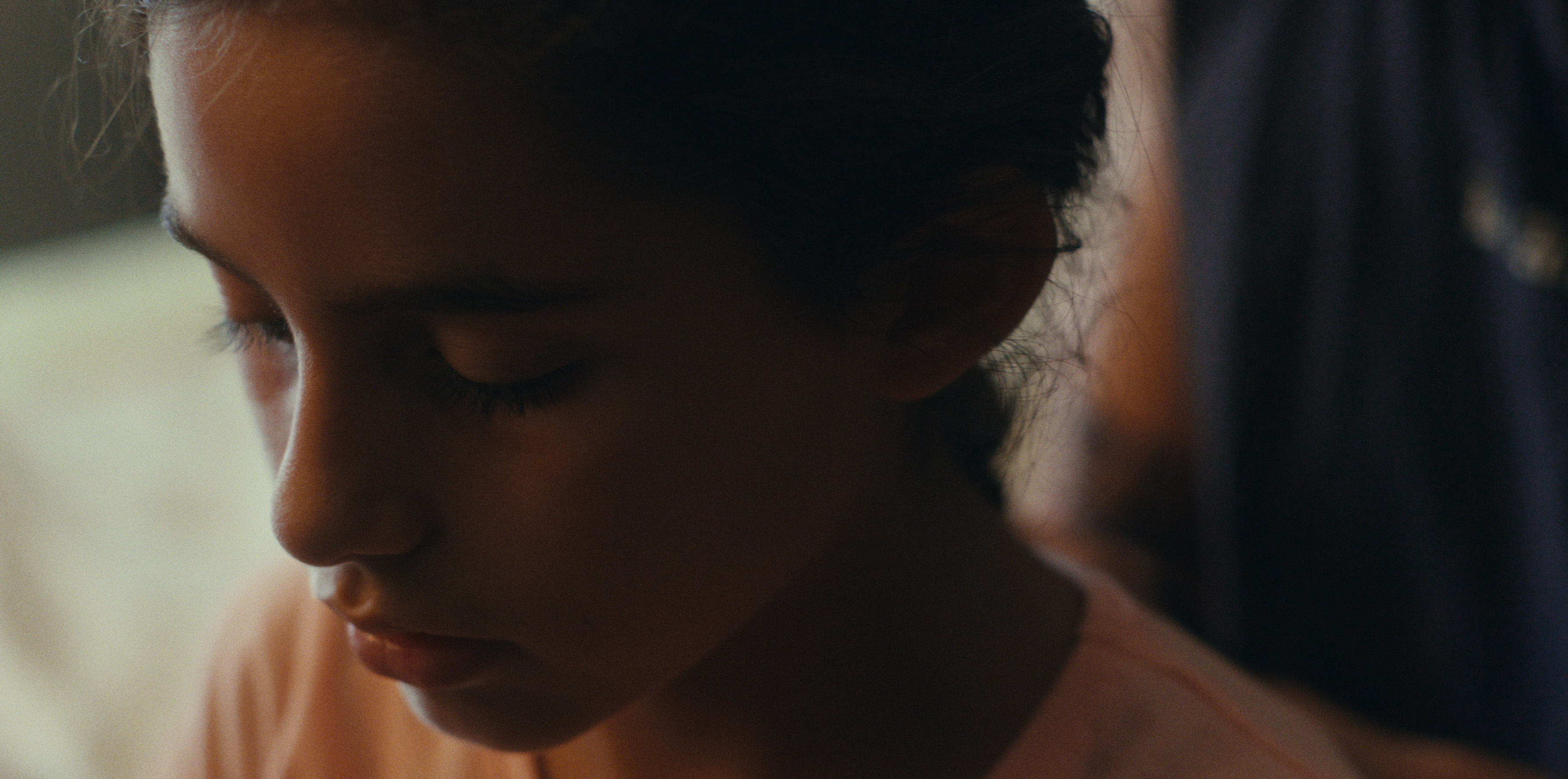 A close-up of a child and an adult in soft daylight