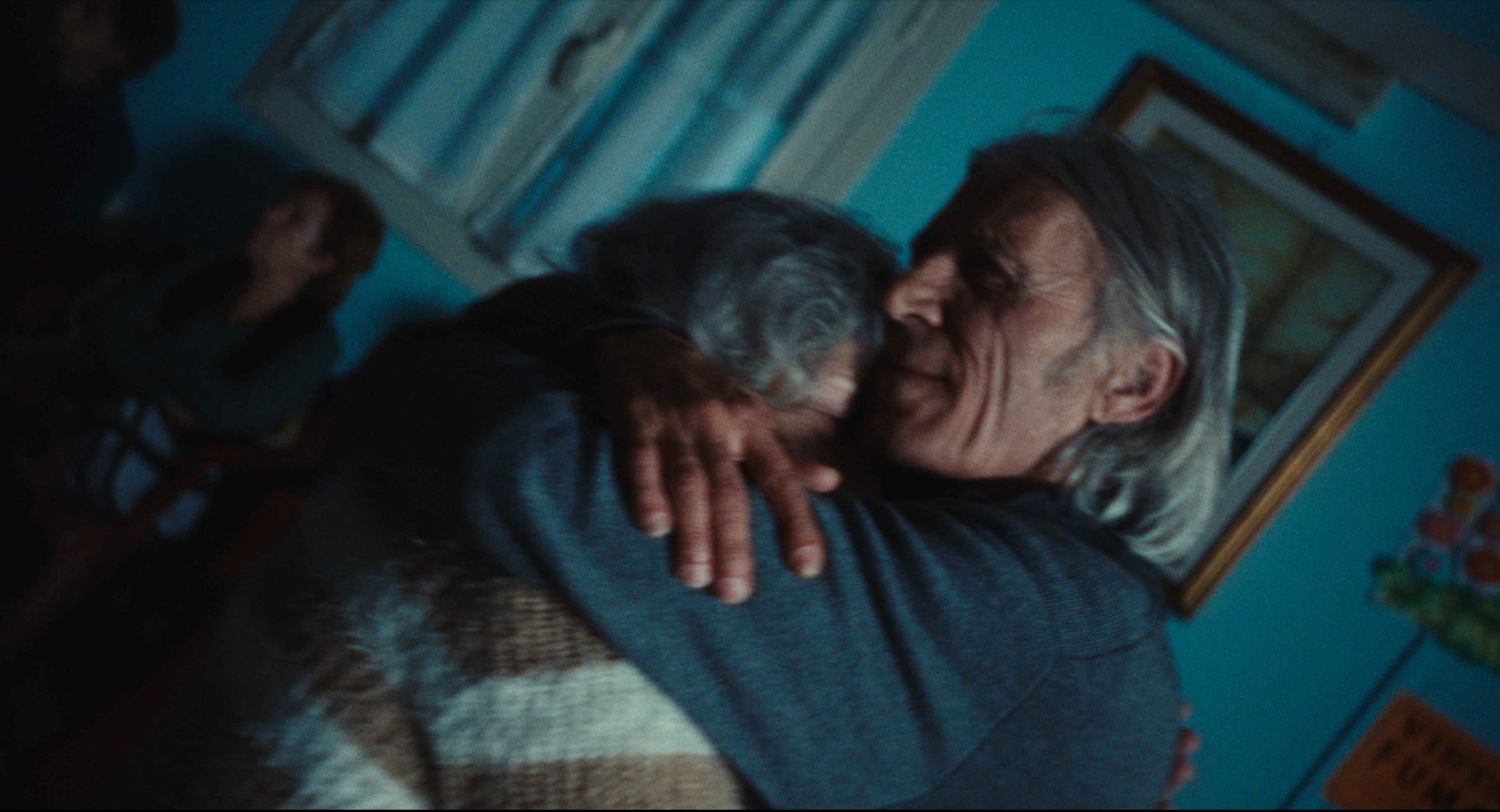 An older man in a blue room holding his hands out