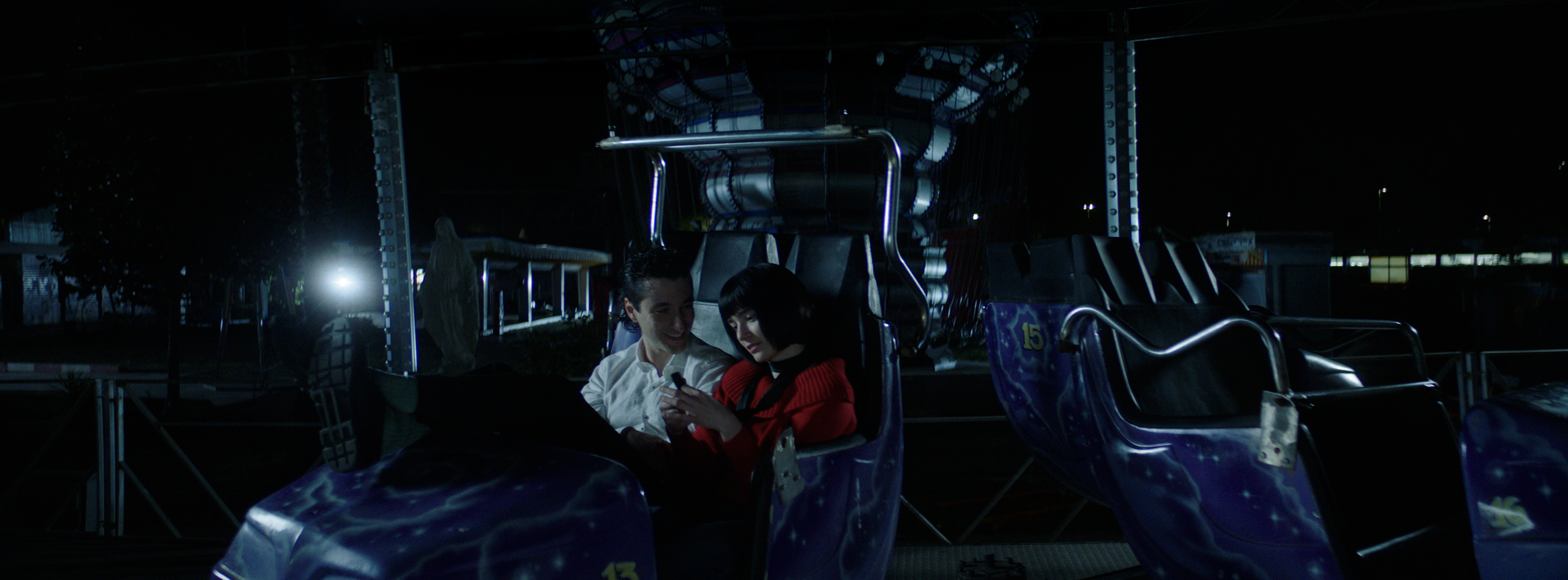 A couple sitting together on a fairground ride at night