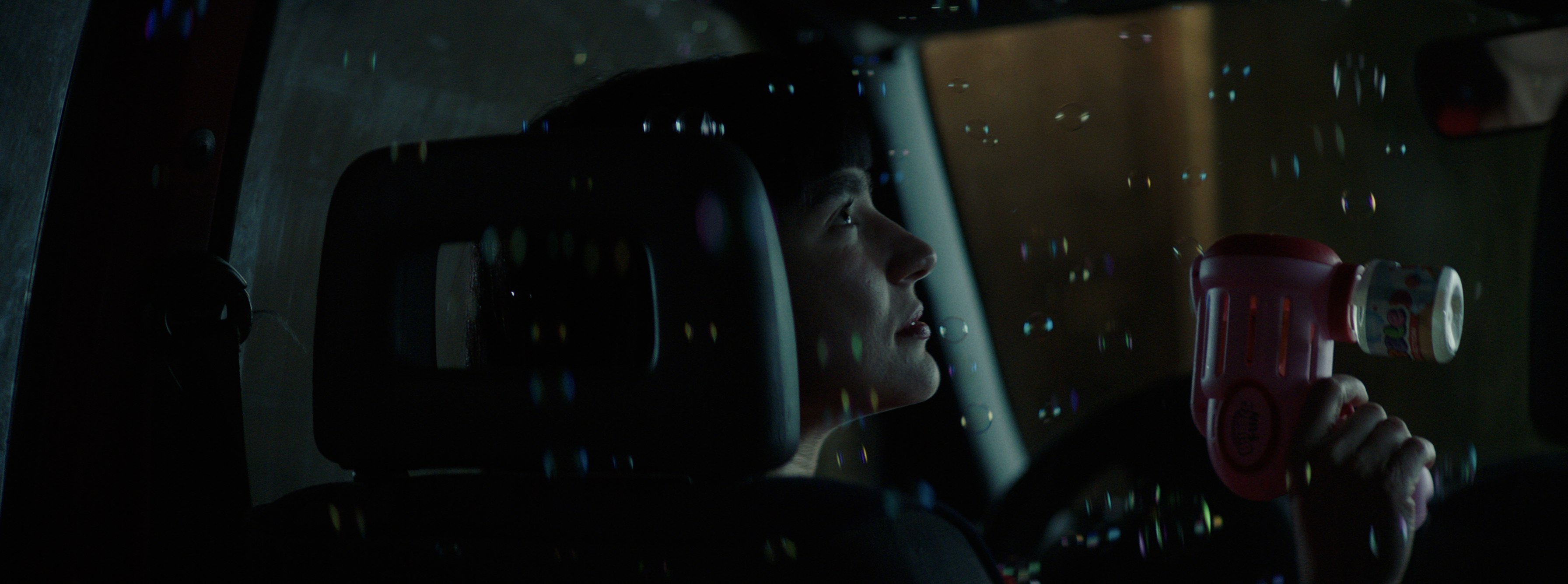 A young man with a bubble toy inside a car