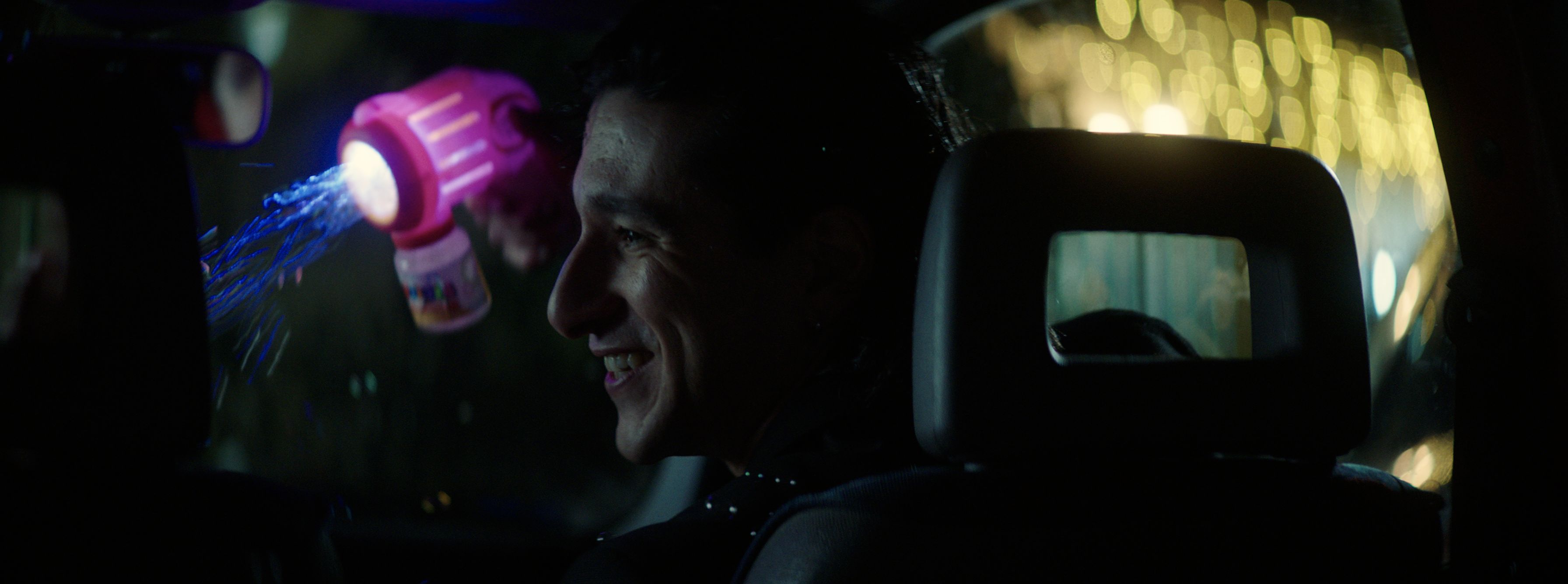 A smiling young man surrounded by bubbles and night lights
