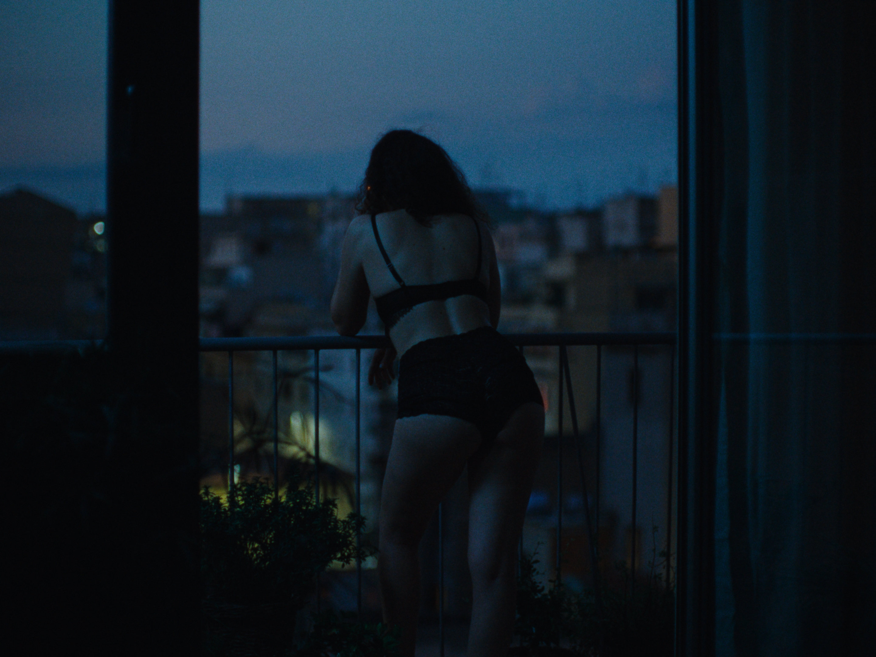 A woman looking over a balcony at dusk