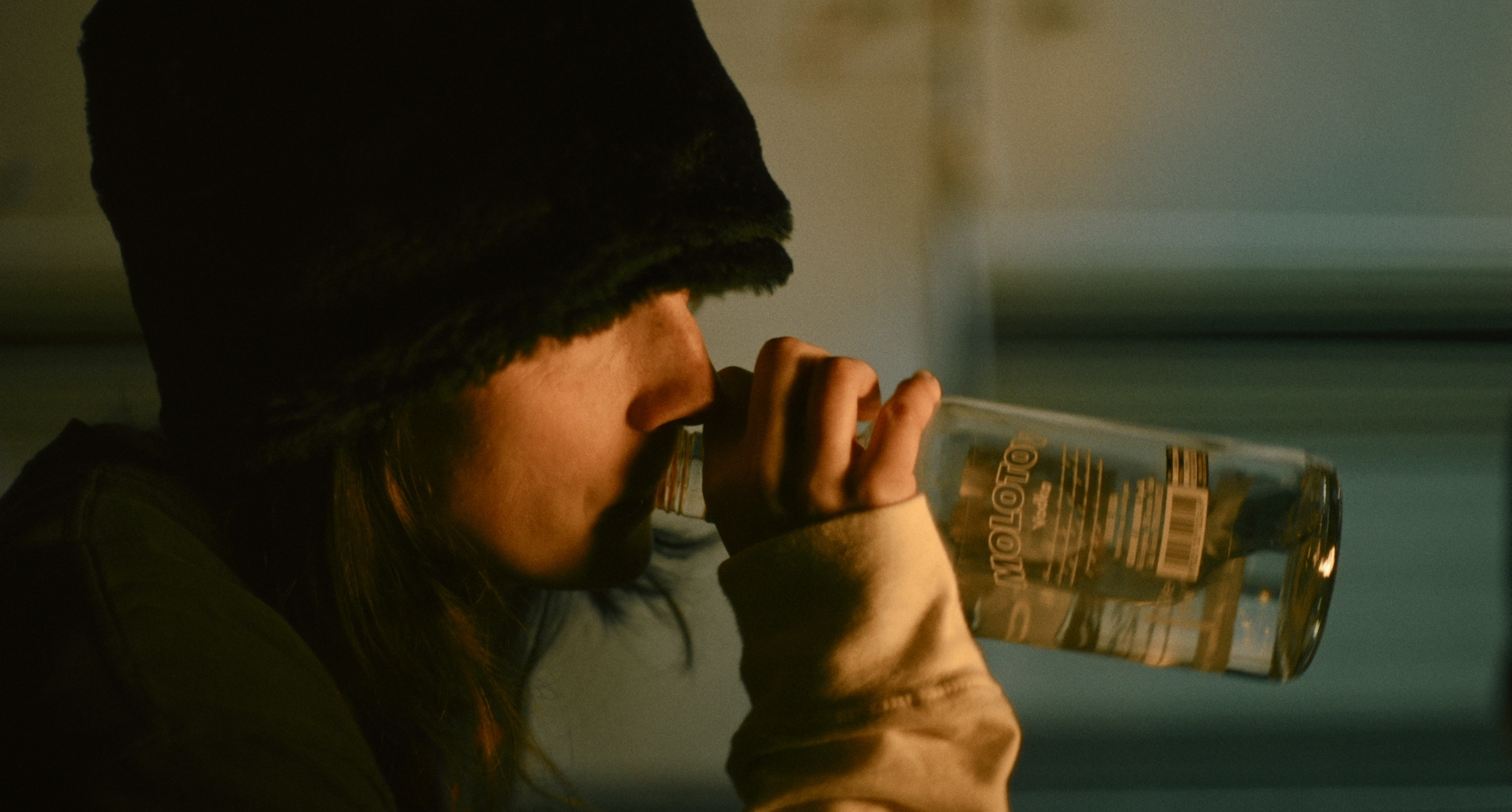A woman drinking from a bottle in warm light