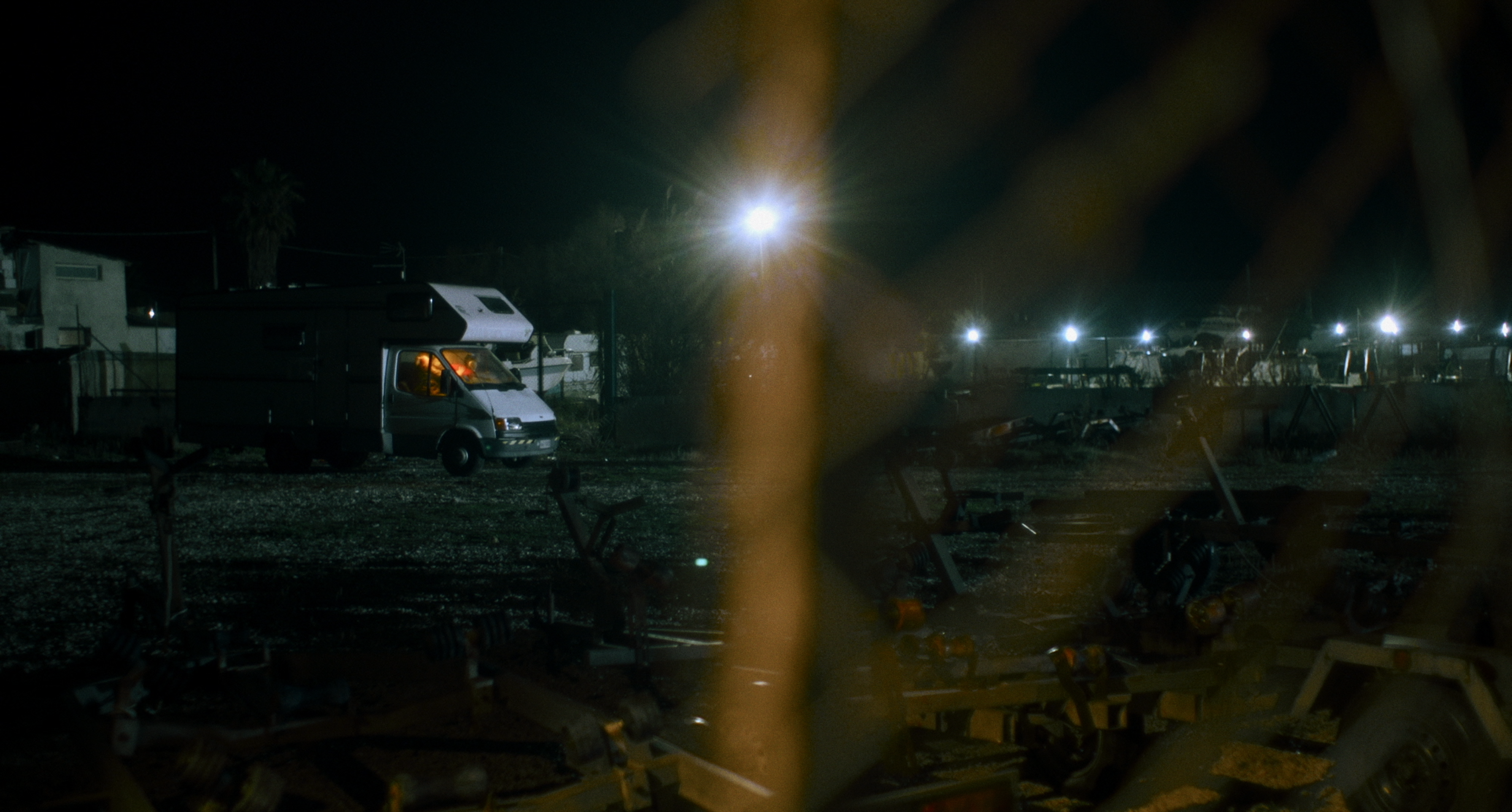 A camper van beneath lights by the beach at night