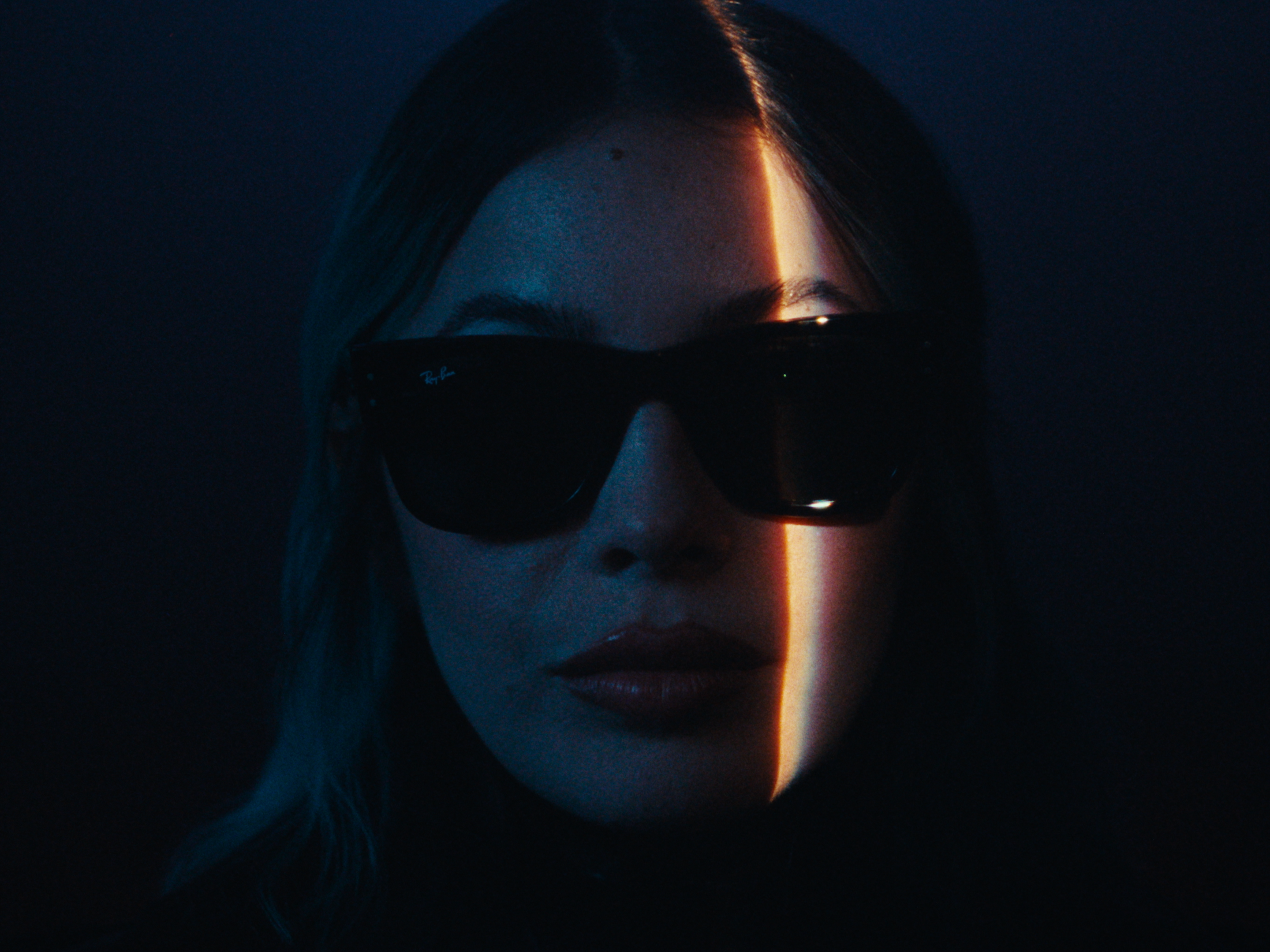 A close-up wearing sunglasses with a narrow band of warm light