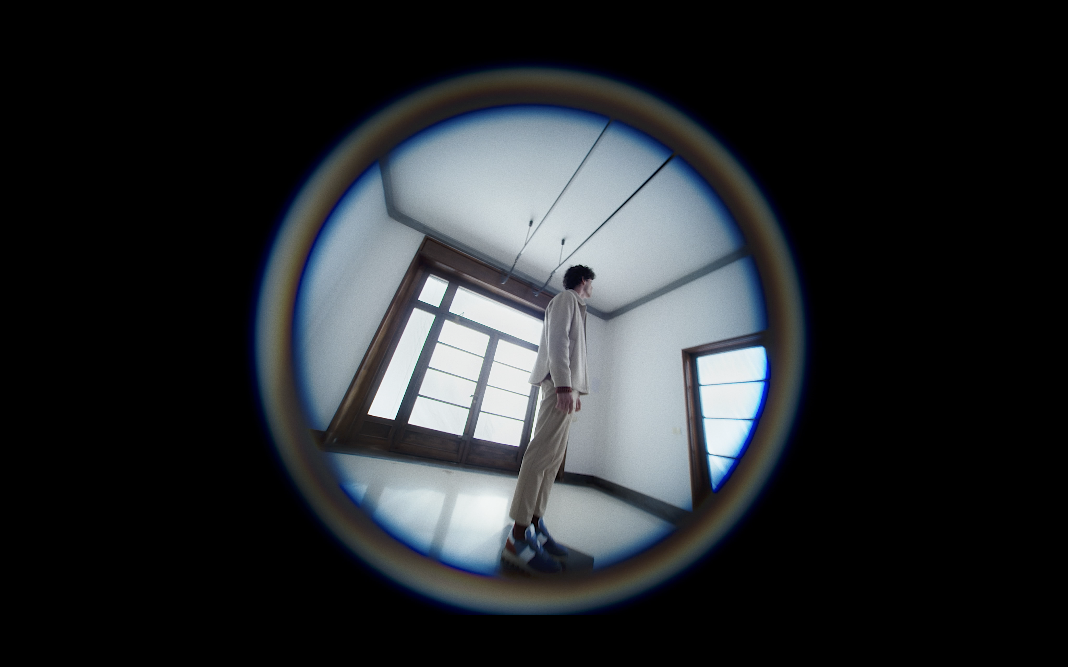 A man wearing sneakers seen through a circular lens in a bright room