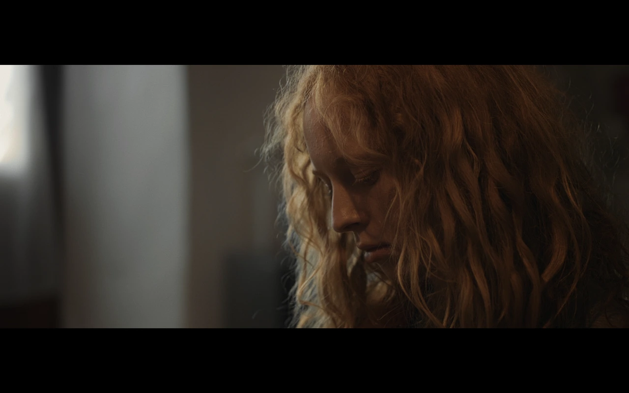 A portrait of a red-haired girl beside a window