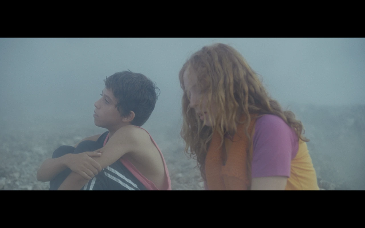 Two children sitting beside the sea in mist