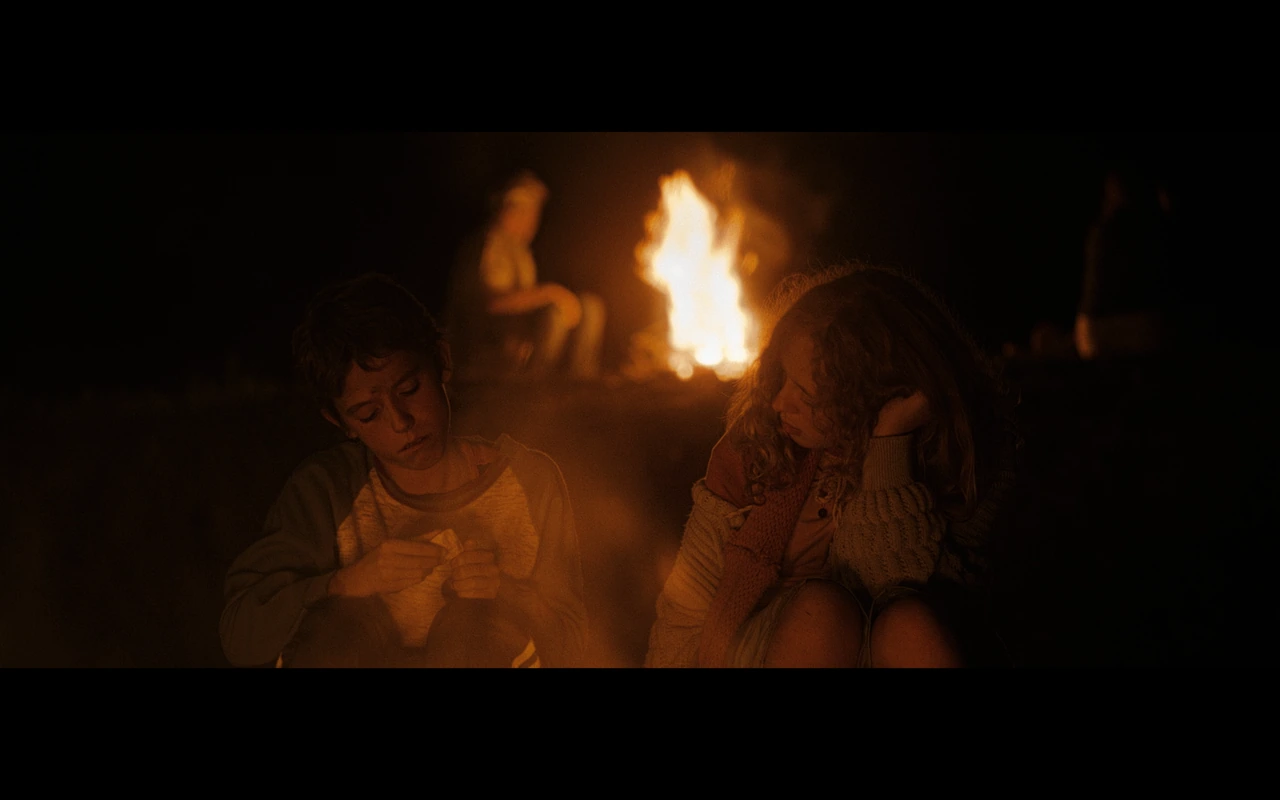 Two children beside a bonfire at night