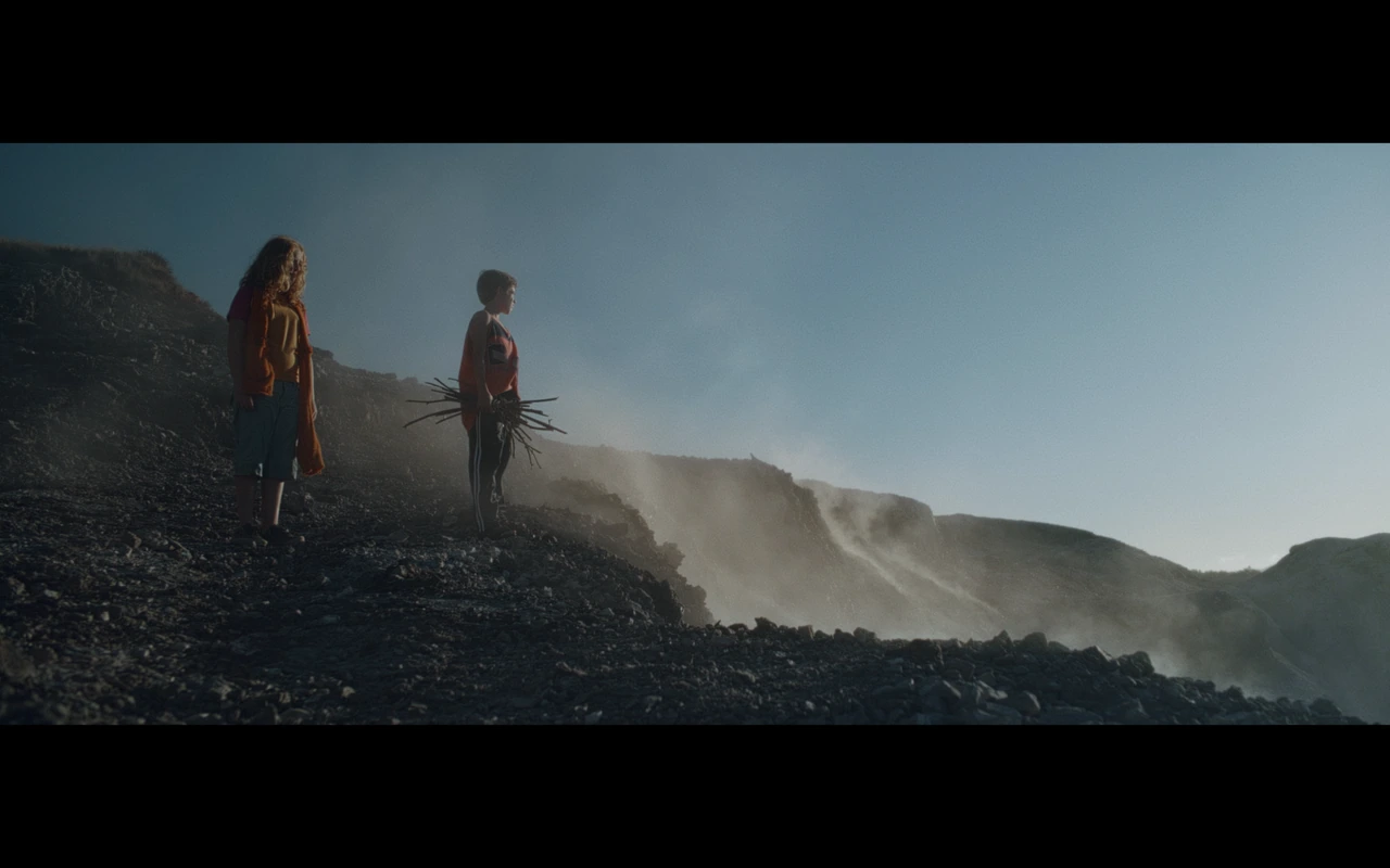 Two children standing on a rocky coast in mist