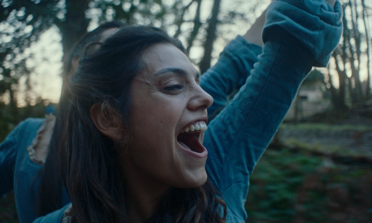 A close-up of a woman raising her arms in the woods