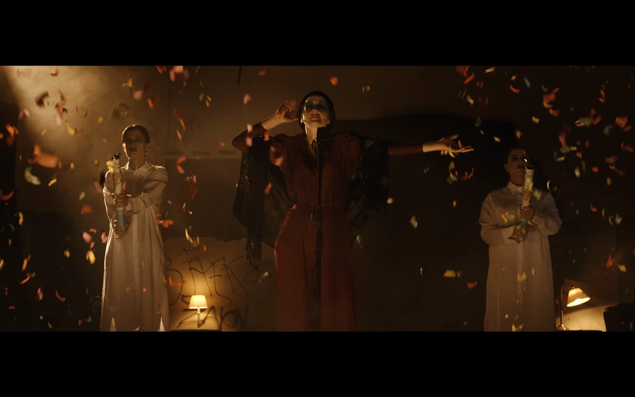 Three performers surrounded by confetti in a warmly lit room