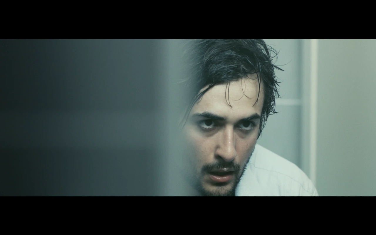 A close-up of a man in a cool-lit bathroom