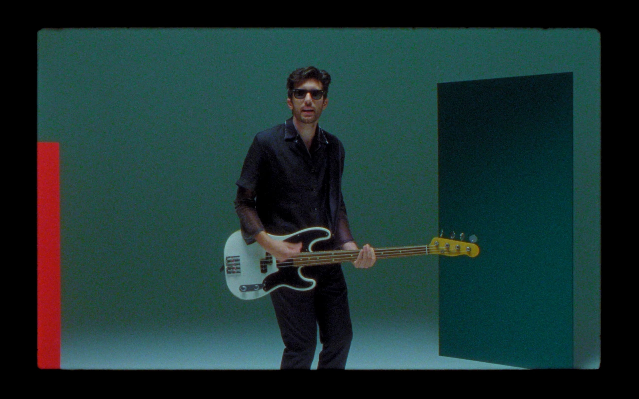 Dodicianni playing bass against a green wall