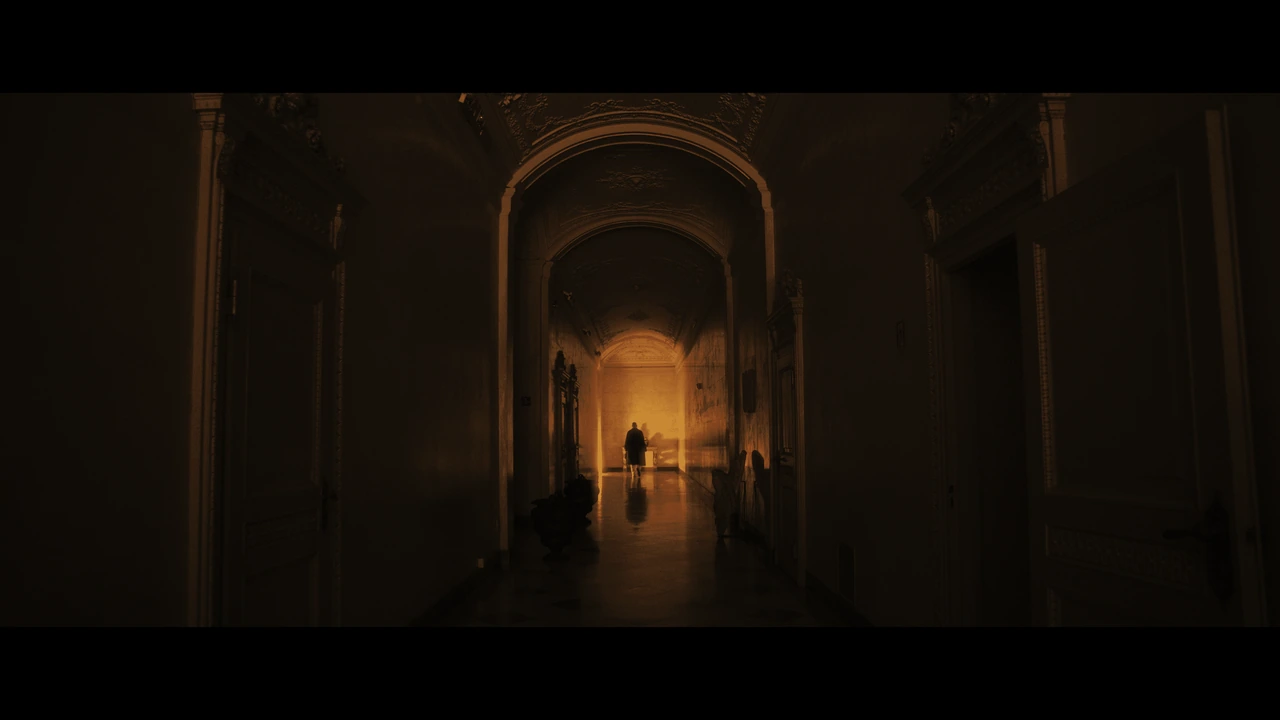 A figure at the end of a grand corridor in golden light