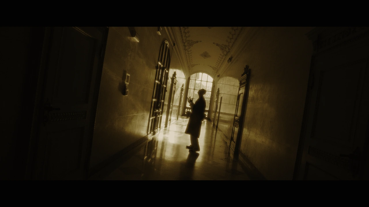 A silhouetted artist in a sloping golden-lit corridor