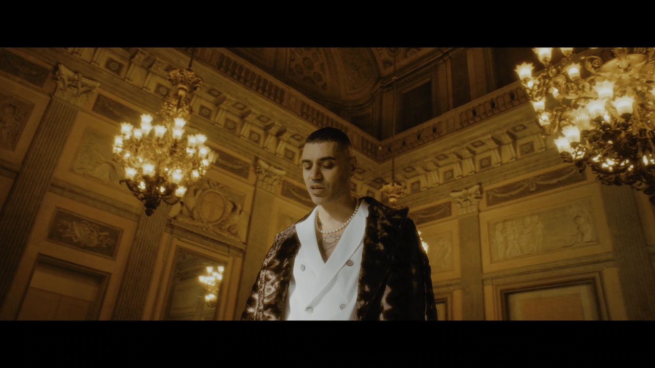 A portrait of an artist beneath chandeliers in golden light
