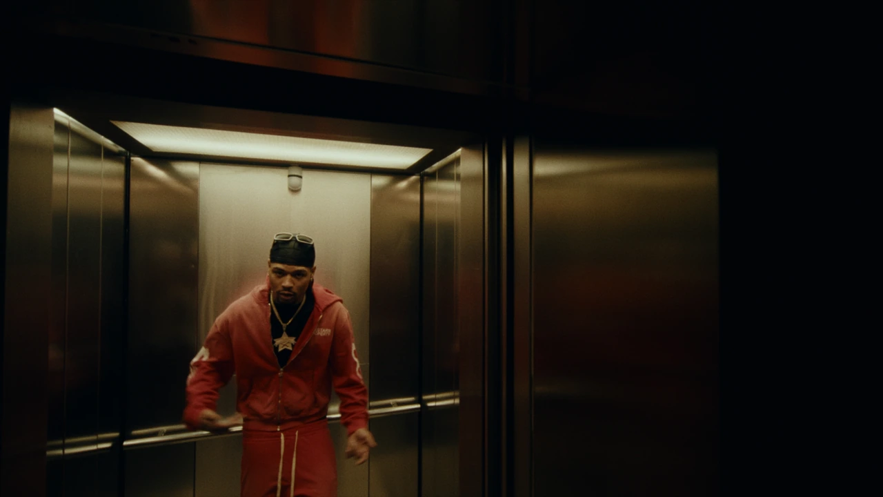 An artist in a red tracksuit inside an elevator
