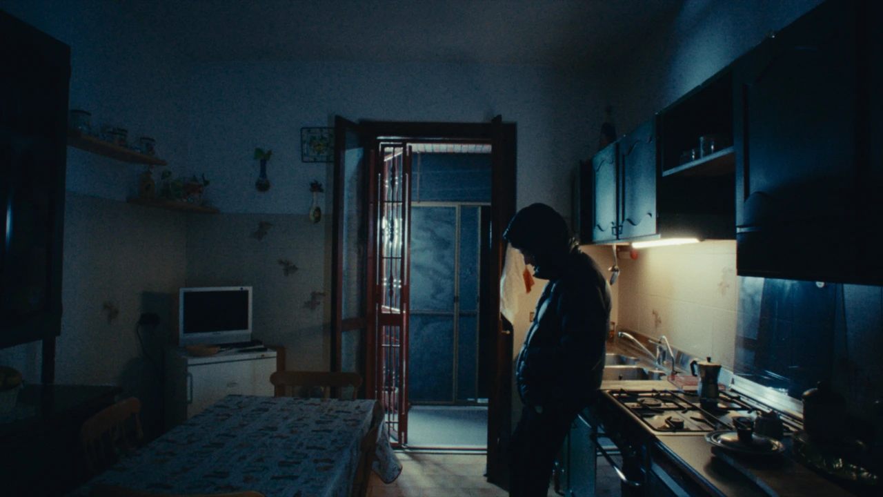 A hooded figure in a kitchen in cool blue light