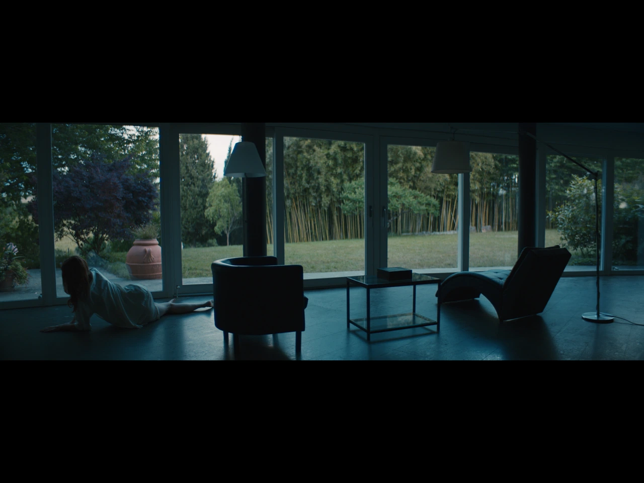 A woman on the floor beside garden-facing windows