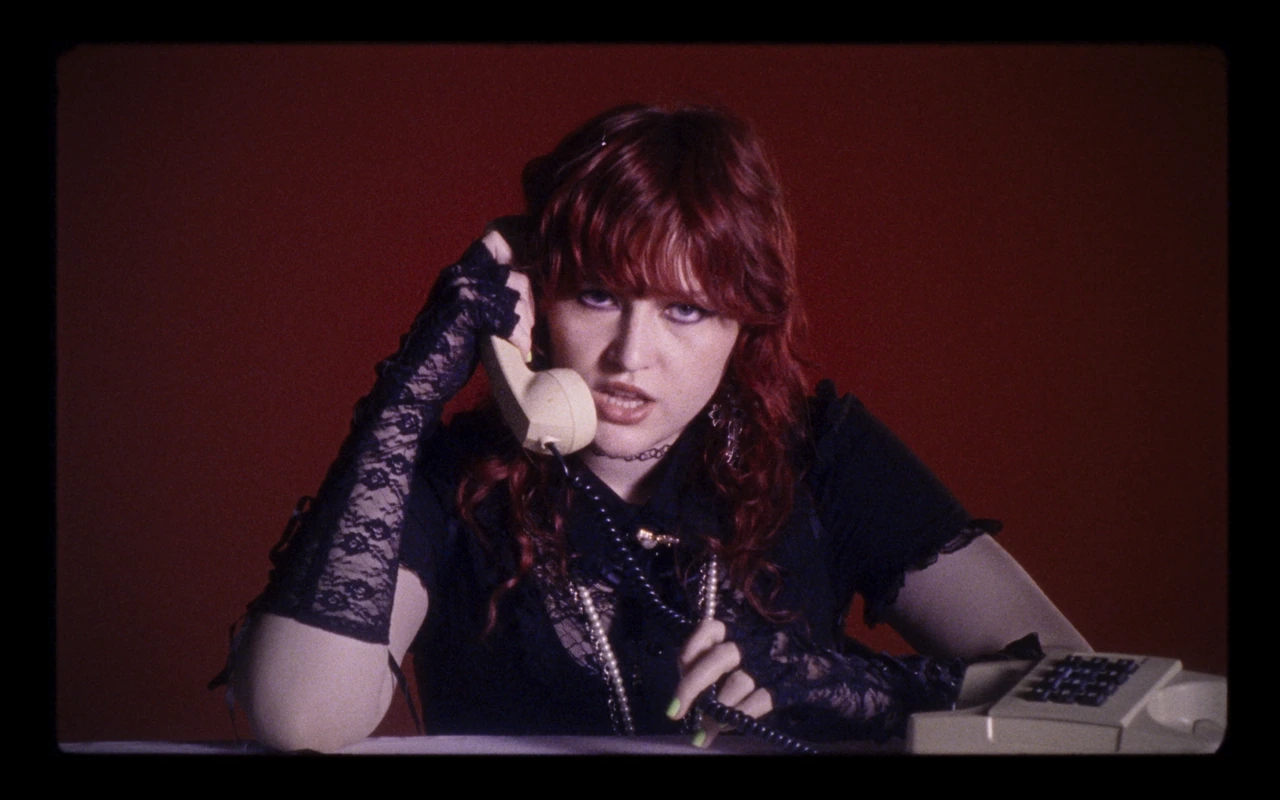 Karin Ann holding a cream telephone against a red wall