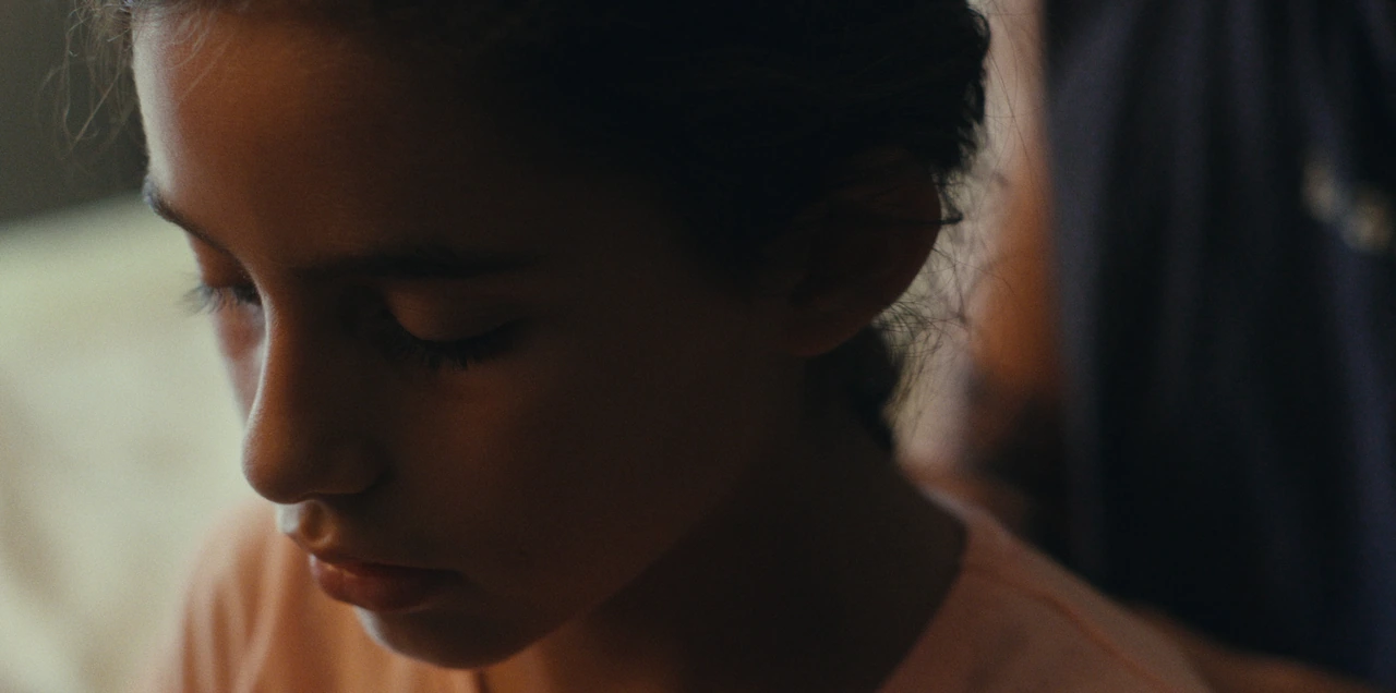 A close-up of a child and an adult in soft daylight