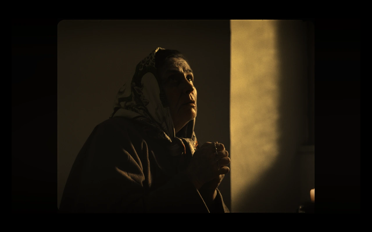 An older woman praying in warm light
