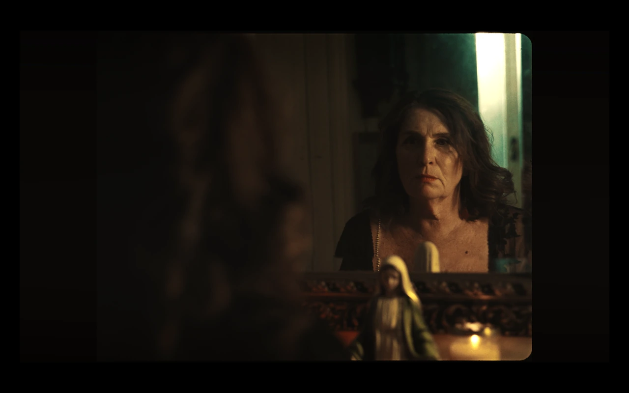 An older woman reflected in a mirror beside candles
