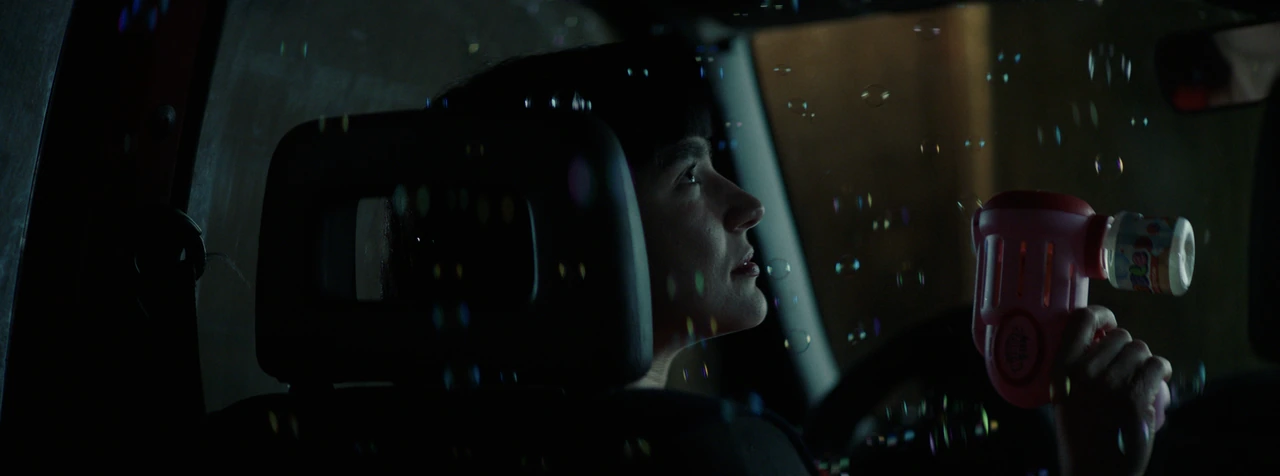 A young man with a bubble toy inside a car