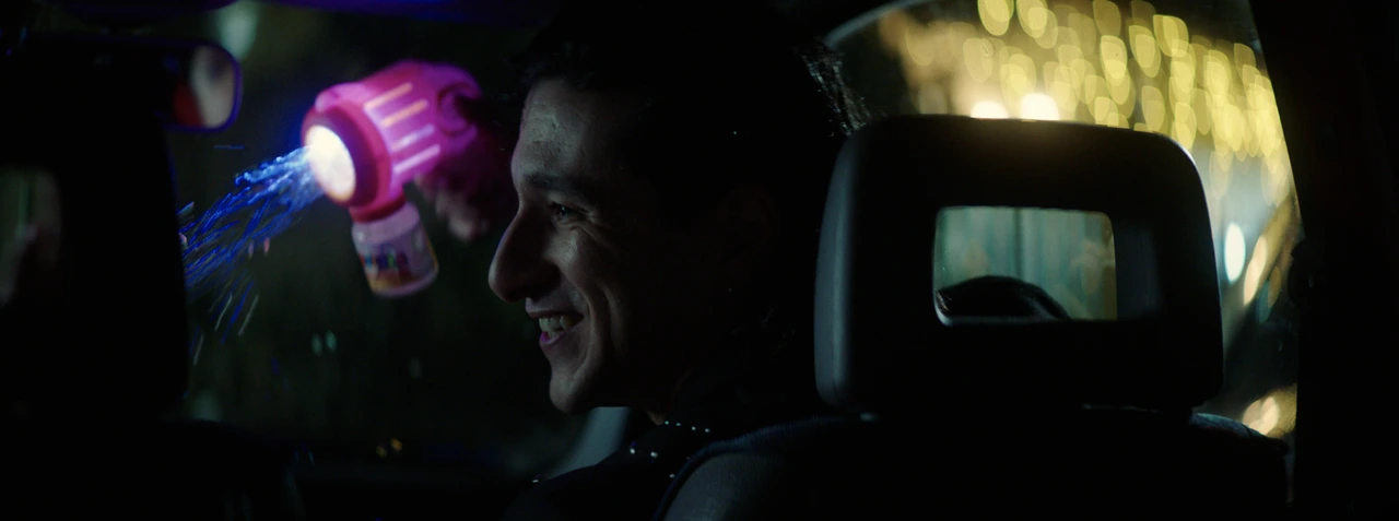 A smiling young man surrounded by bubbles and night lights
