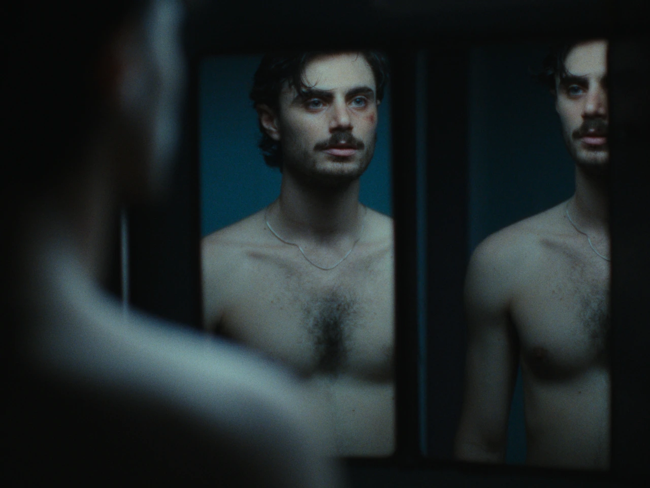 A man reflected in a mirror in blue light
