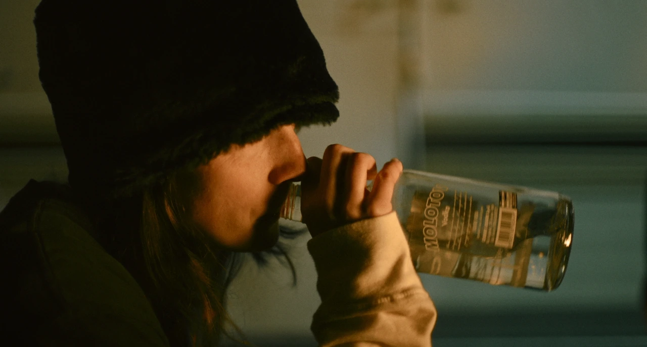 A woman drinking from a bottle in warm light