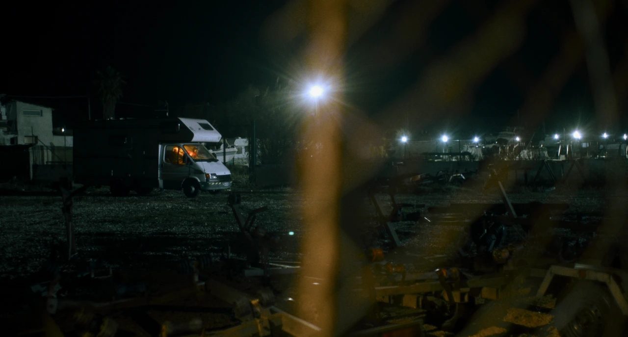 A camper van beneath lights by the beach at night