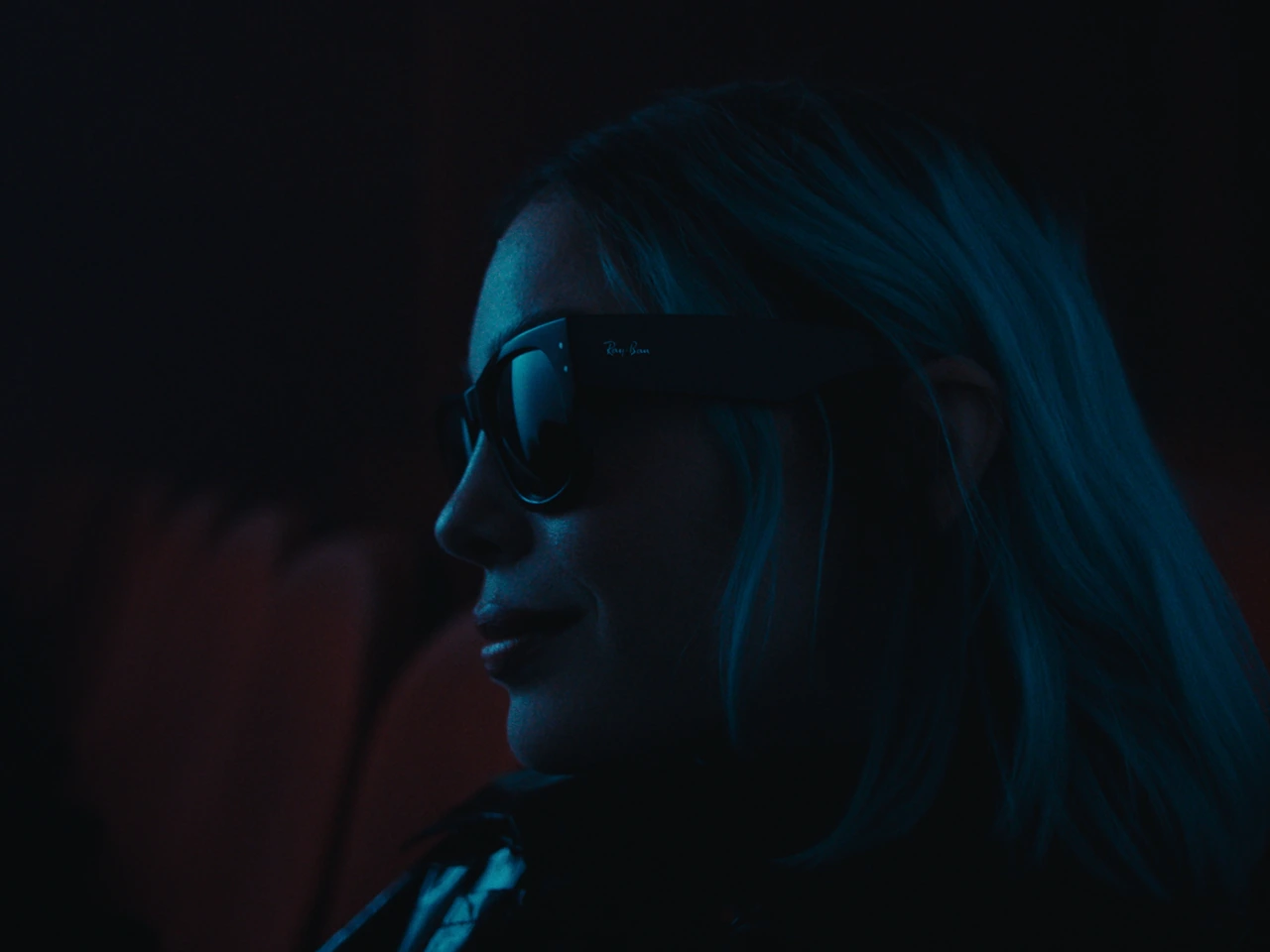 A profile wearing Ray-Ban sunglasses in blue light