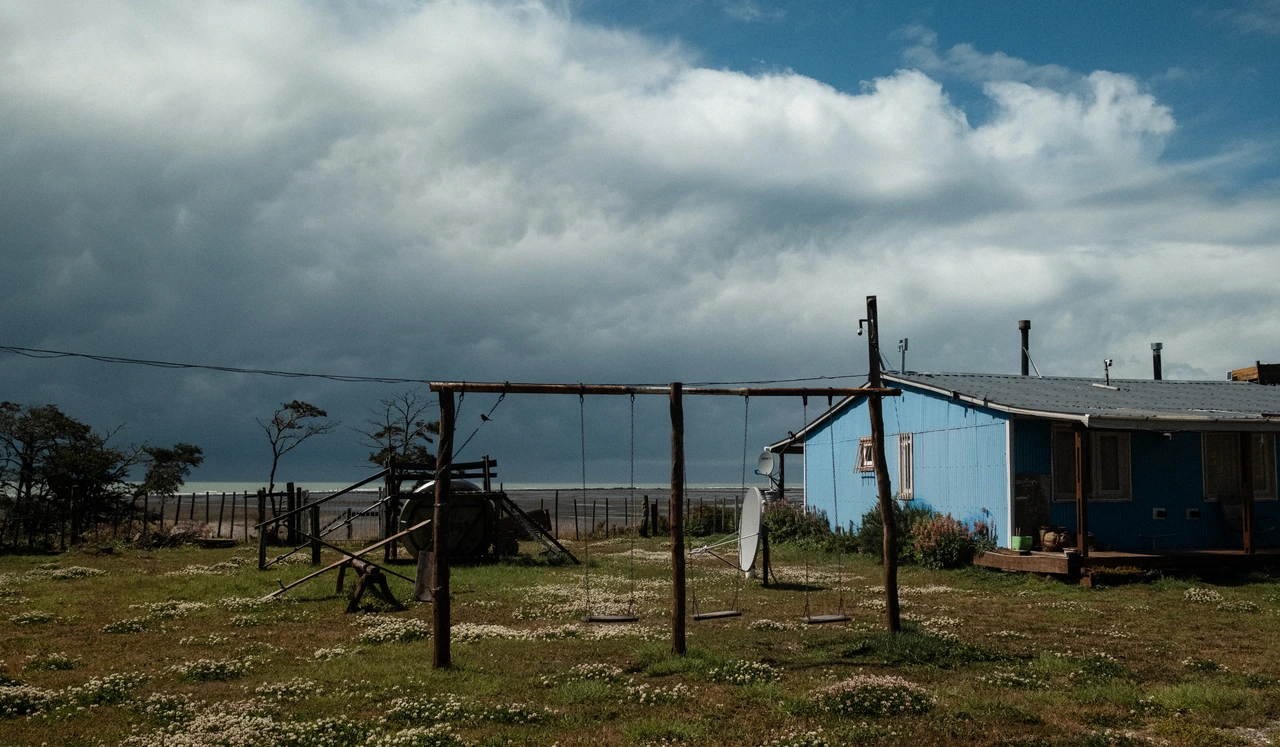 A blue house beneath a broad cloud-filled sky