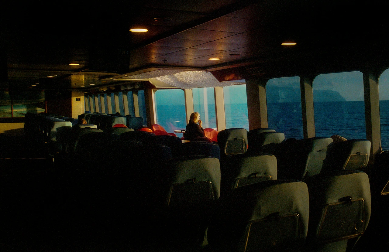 A passenger seated beside the windows of a ferry