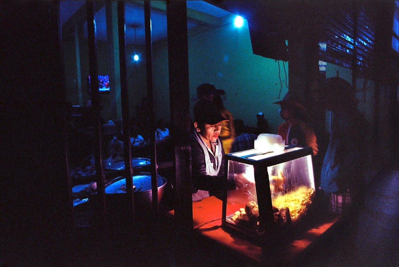 A street vendor illuminated by warm and blue light at night