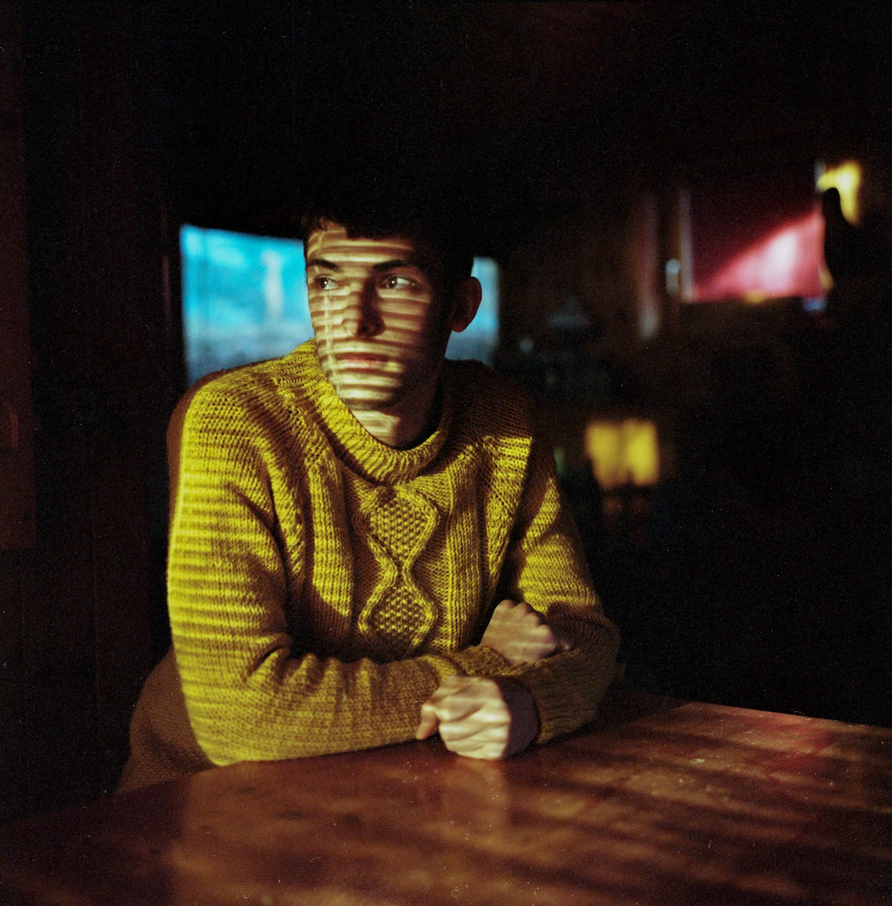 A portrait at a table crossed by narrow bands of light