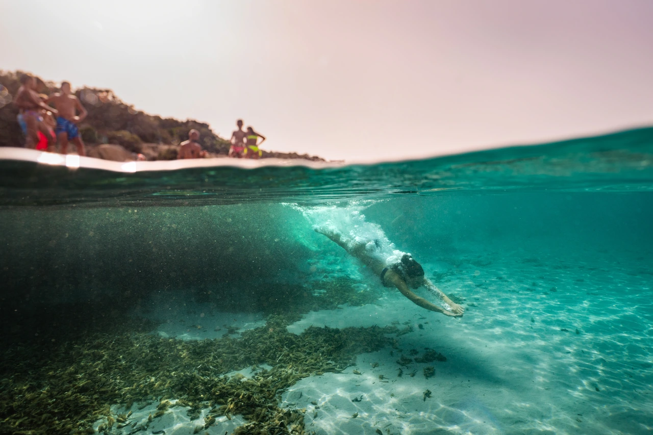 A swimmer diving beneath the surface of turquoise water